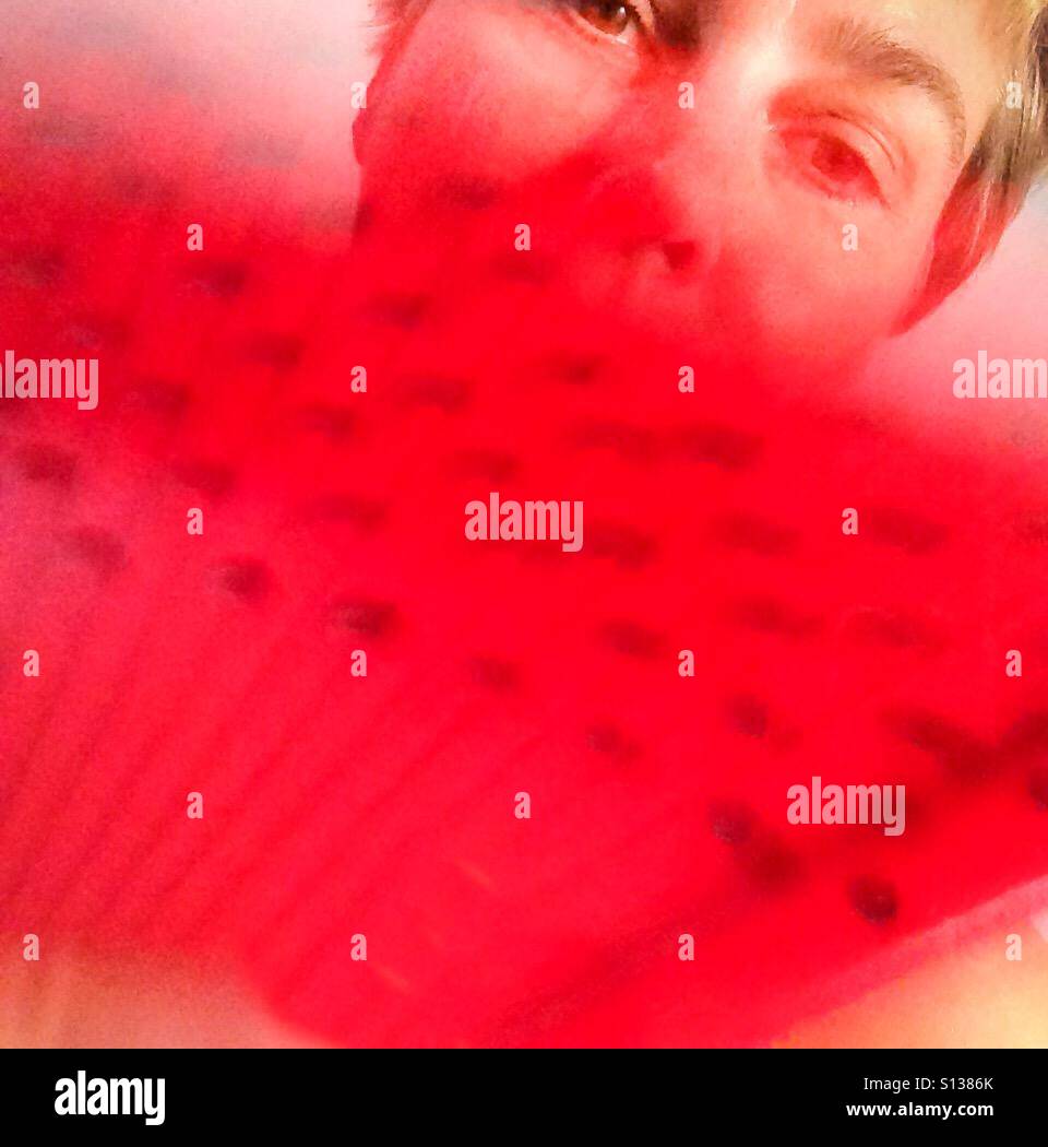Ventaglio rosso con punti sventolate davanti a un signore faccia. Foto Stock