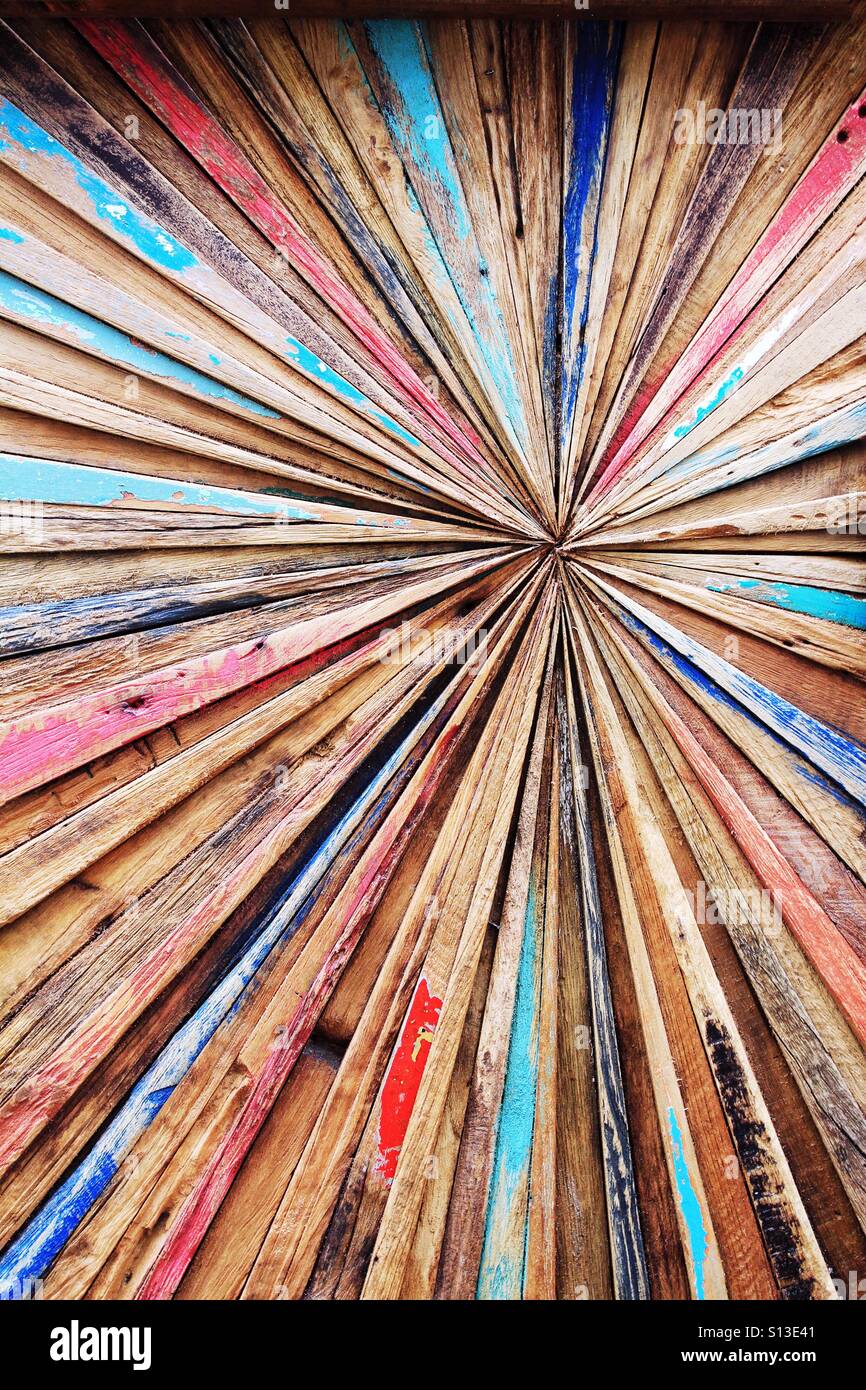 Un'arte astratta sfondo costituito da strisce colorate di vecchio legno deriva che convergono in un punto centrale. Foto Stock