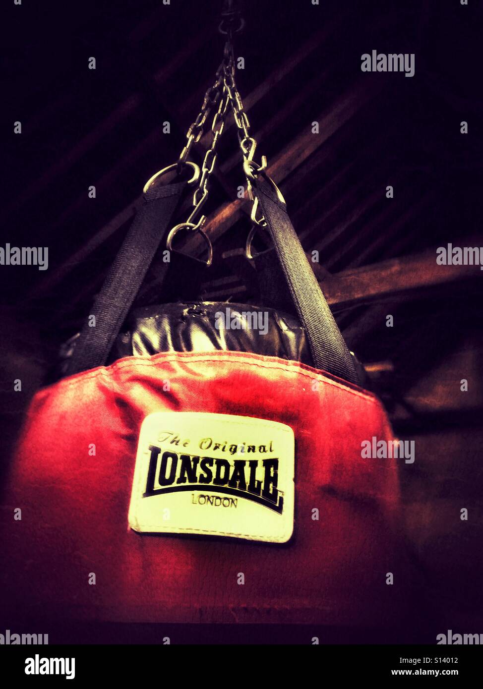 Una catena pende da puntoni che sospende una Lonsdale punch bag Foto Stock