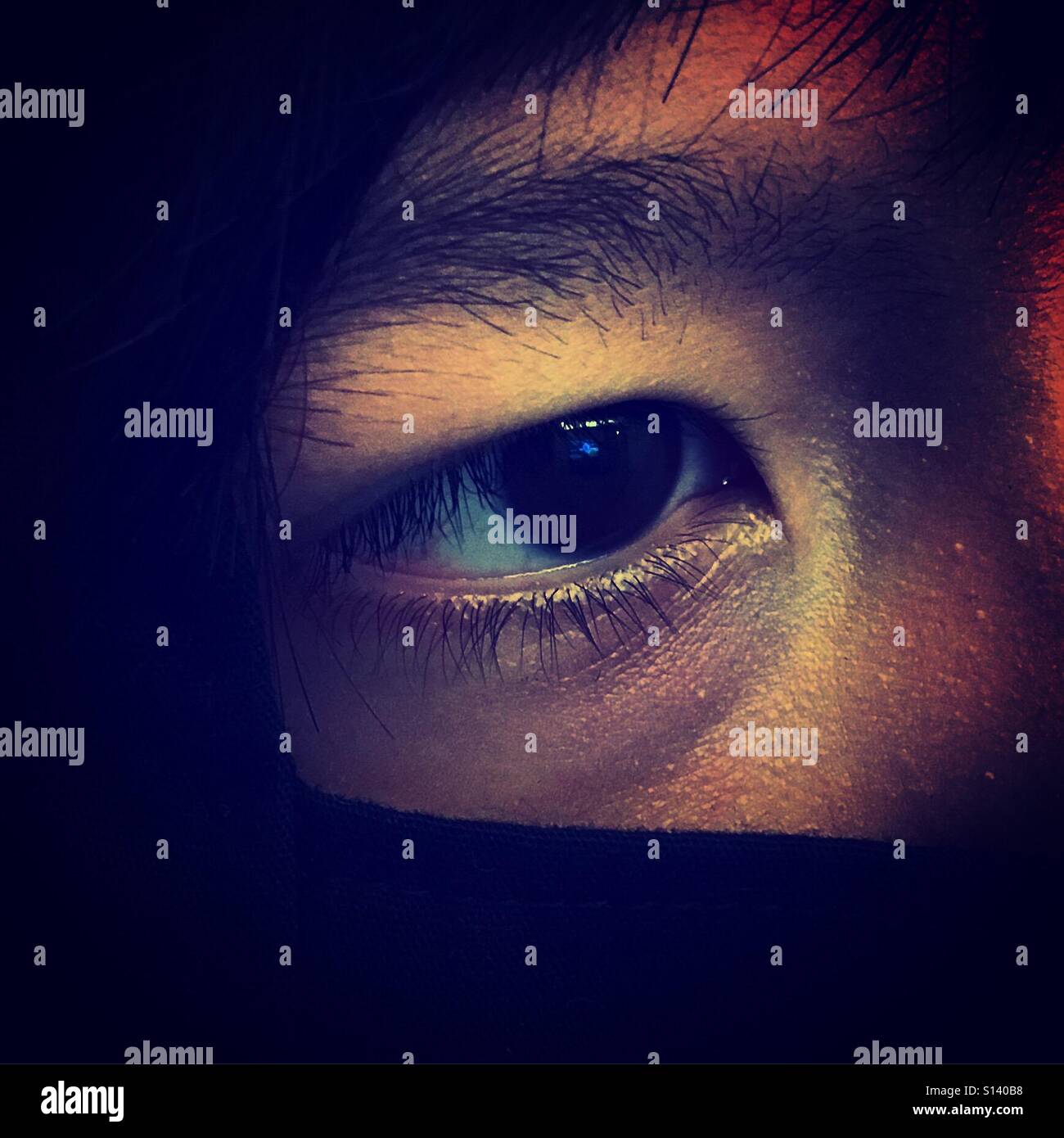Prima piano su un occhio di un ragazzo asiatico che guarda o spiava qualcosa di interessante - Immagine stock catturata con smartphone