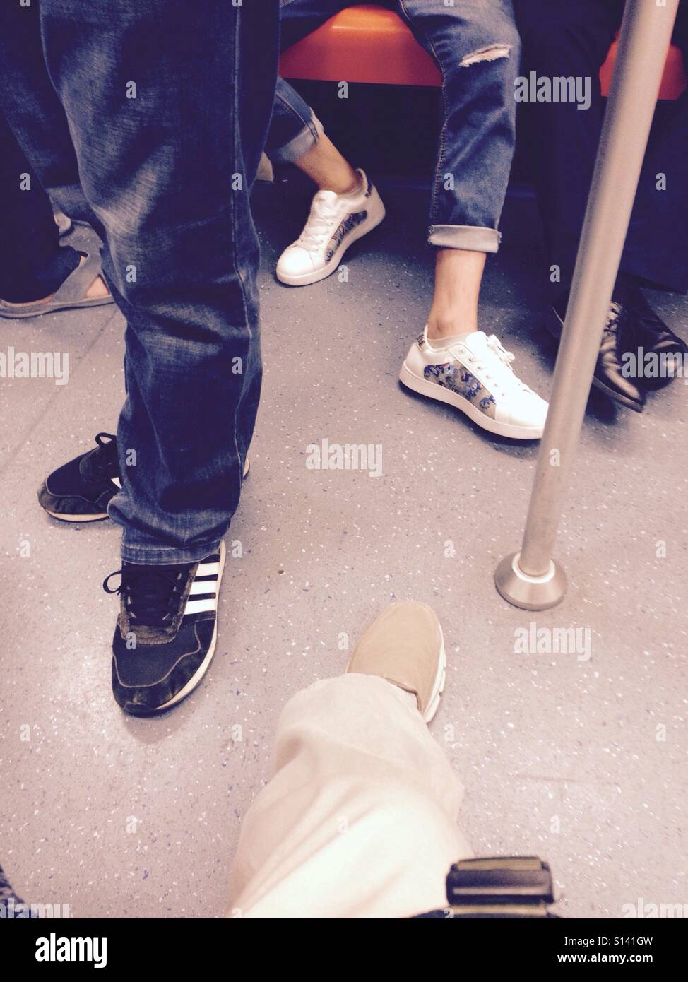 Paia di scarpe e le gambe di un treno della metropolitana compreso il nero, bianco e grigio scarpe Foto Stock