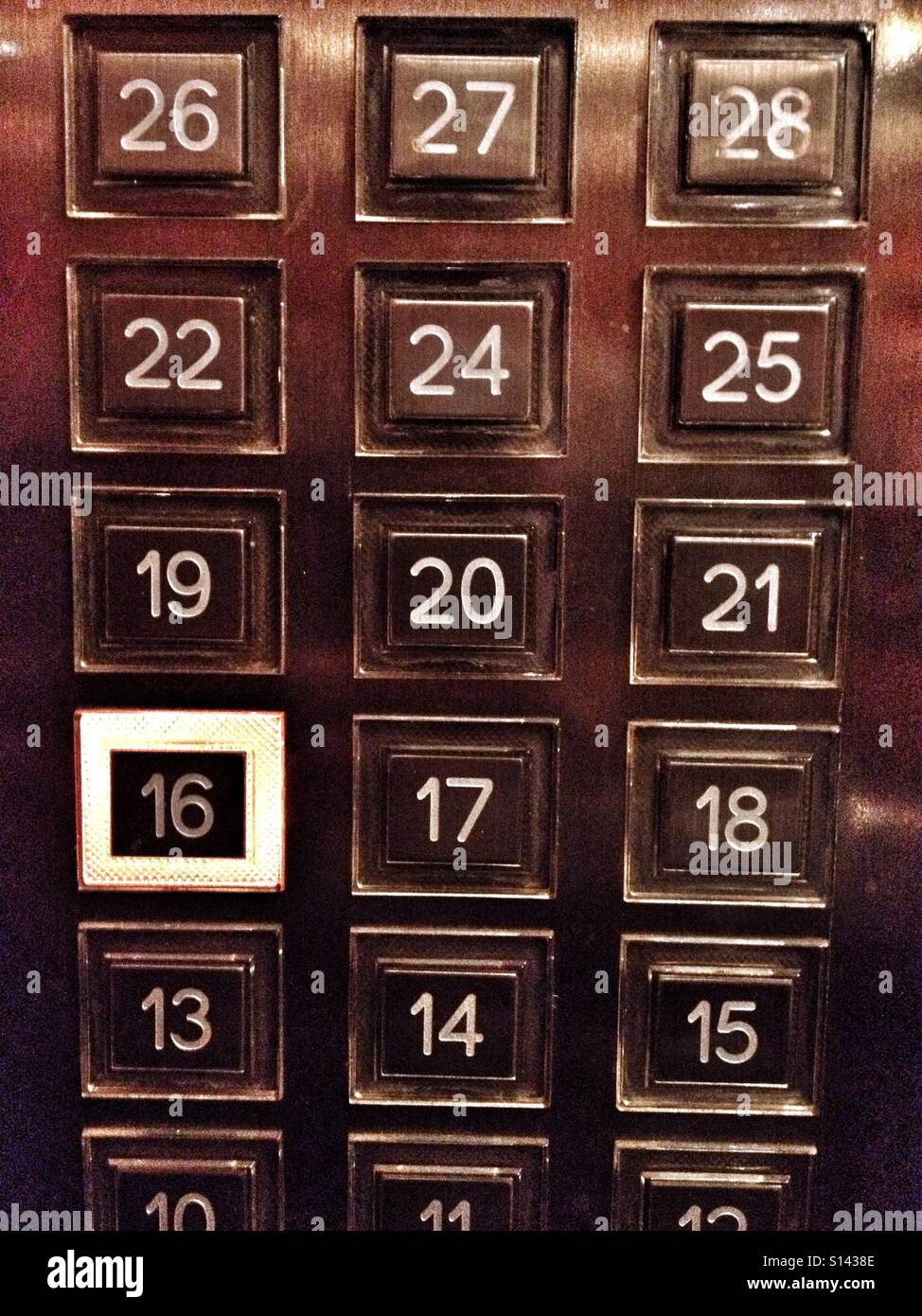 Pannello di ascensore che mostra piani 10 a 28 con numero di pavimento 16 pulsante evidenziato & selezionato Foto Stock