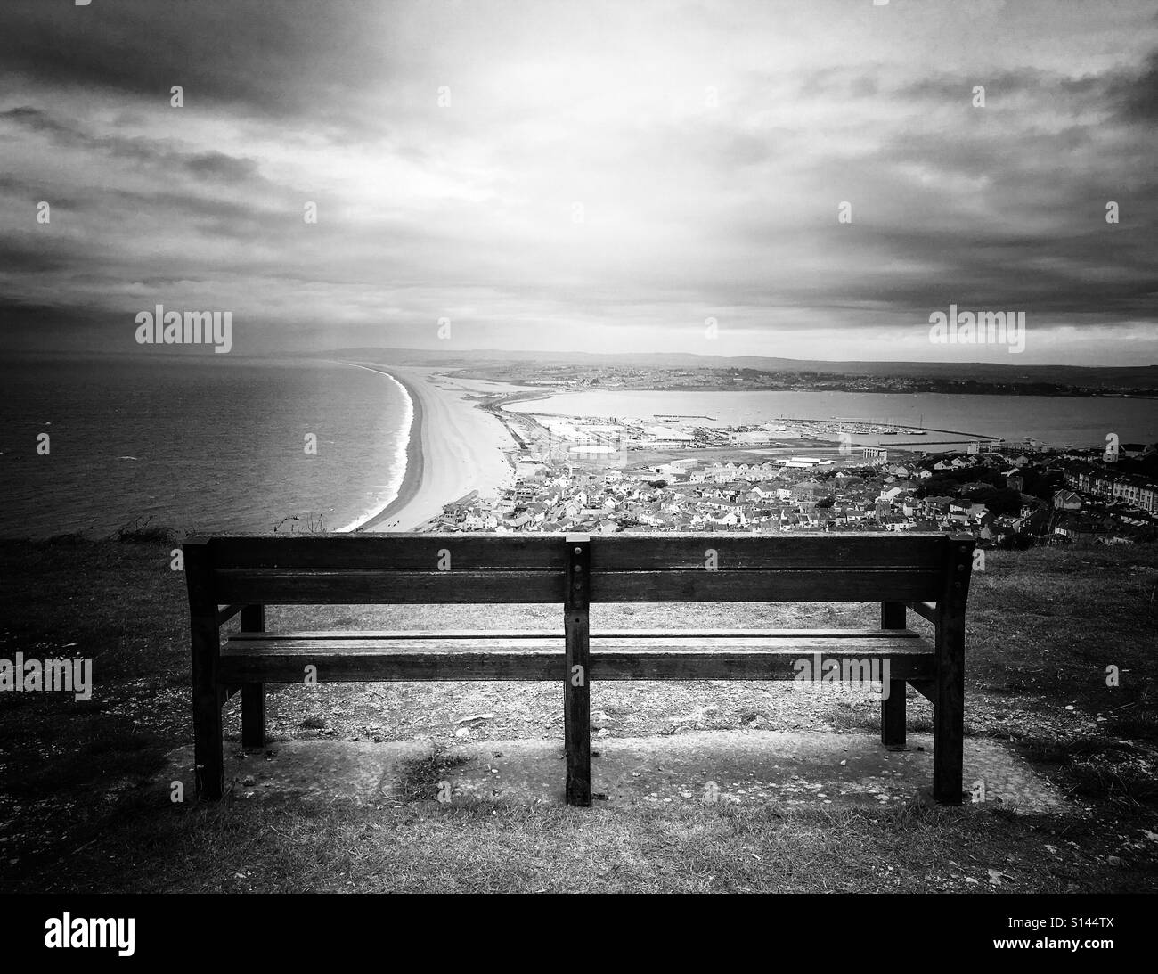 Il fascio di luce sul lone una panchina nel parco che si affaccia sul porto di Weymouth, Regno Unito. Foto Stock