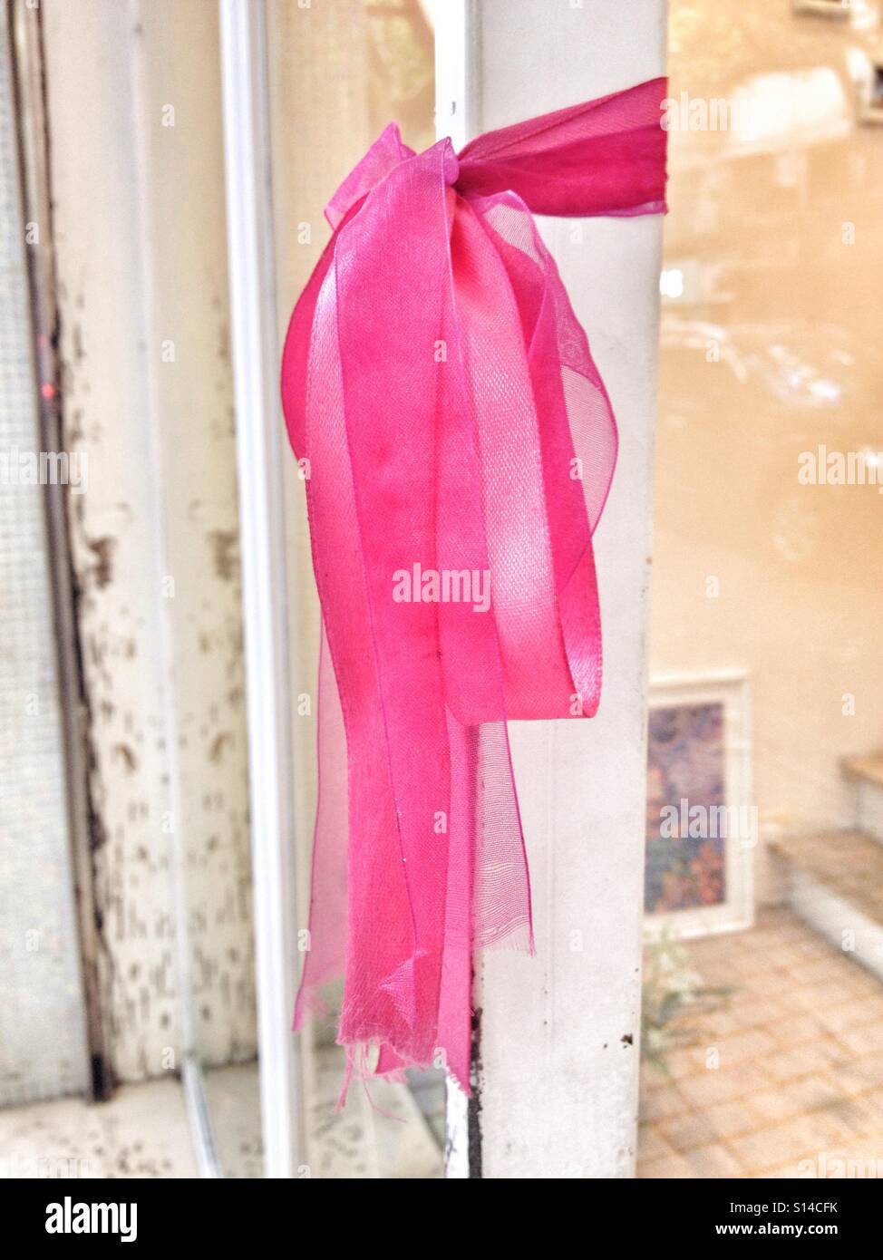 Il cancro al seno nastro rosa legato su bianco Store porta Maniglia di ingresso Foto Stock