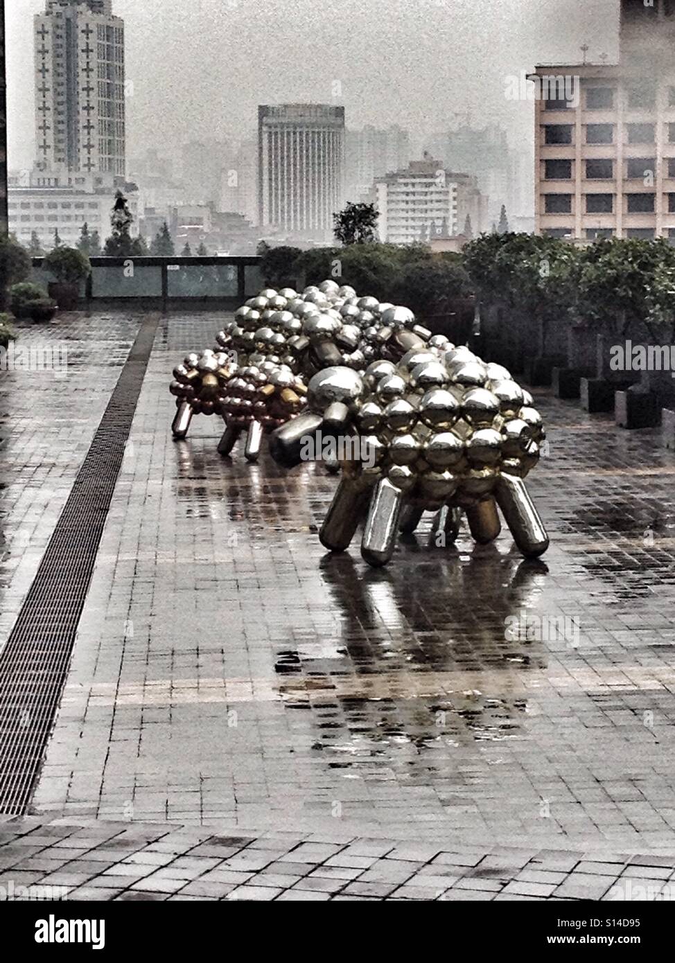 Argento metallico sculture di pecora & Artwork sedersi sotto la pioggia battente Storm Foto Stock