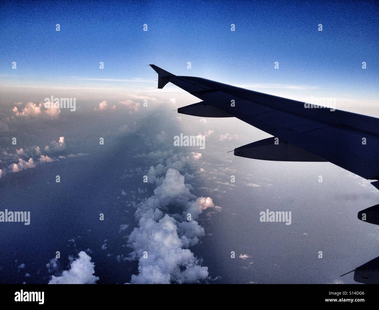 L'ala sinistra di un piano alto sopra le nuvole sopra il cielo blu Foto Stock