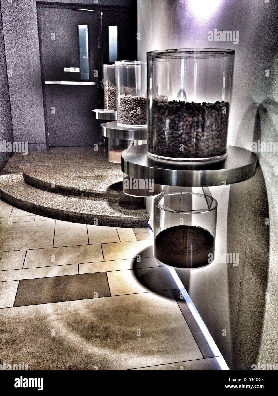 3 Contenitori di chicchi di caffè passando attraverso una smerigliatrice , i chicchi di caffè sulla sommità e la polvere di caffè sul fondo Foto Stock