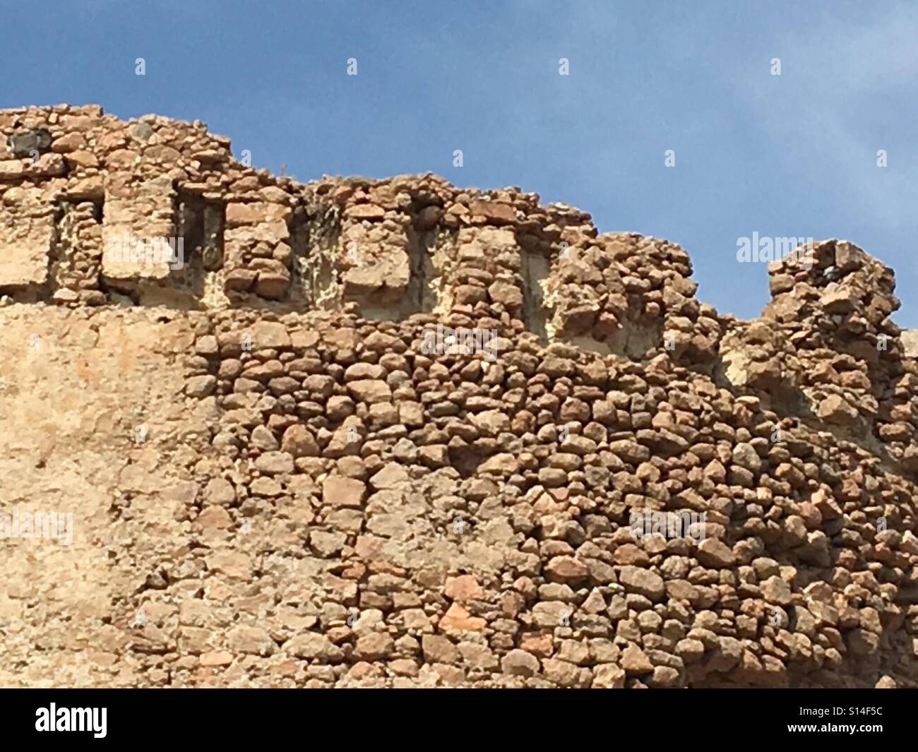 Sgretolamento di merlatura della Torre Spagnola o Torre Spagnola del XVI secolo fortificazione costruita per scopi difensivi sulla costa occidentale della Sardegna, l'Isola Rossa, Settembre - Immagine stock catturata con smartphone