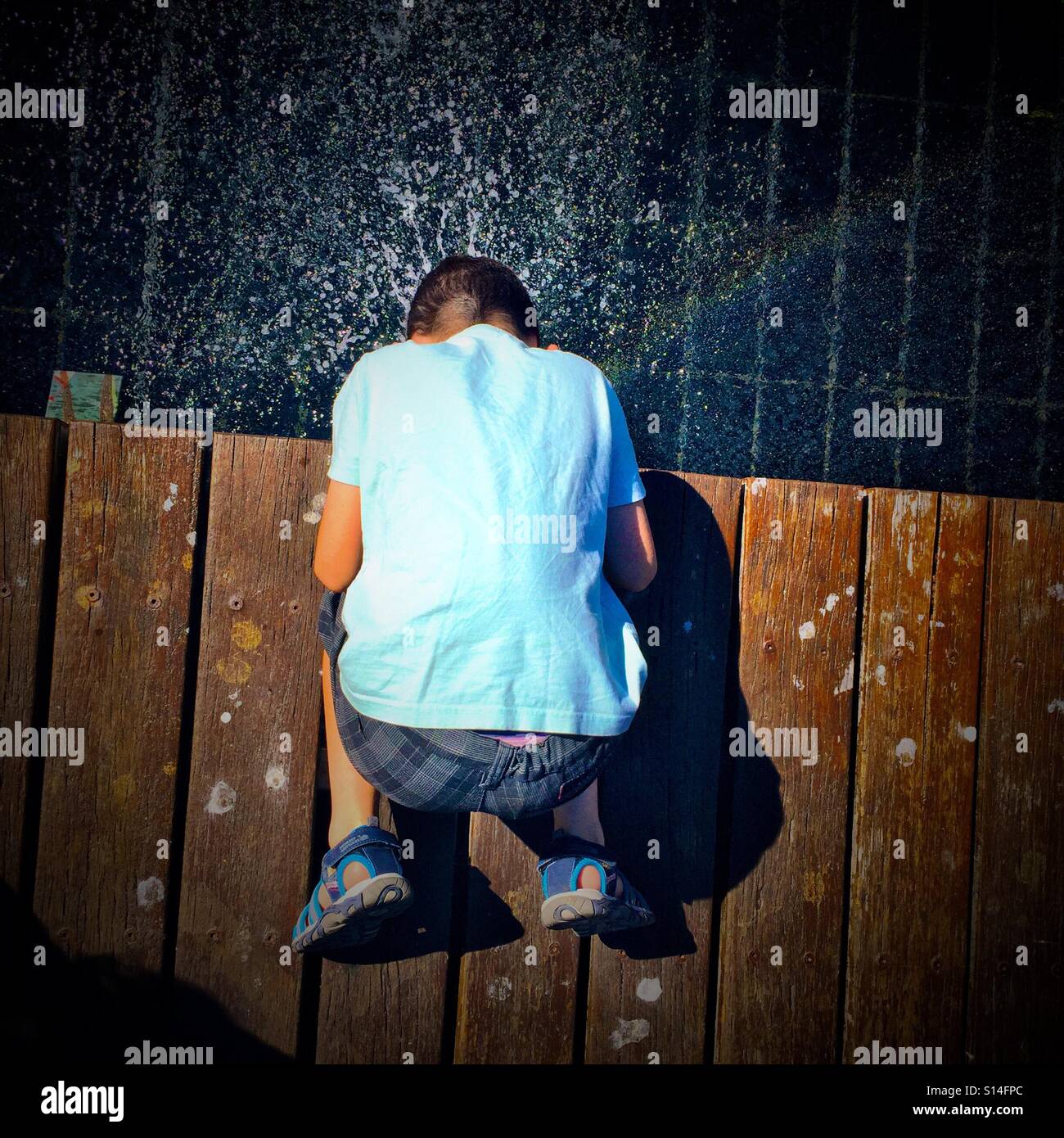 Divertimento estivo in una fontana - 8 anno vecchio ragazzo mettendo la sua testa in una fontana per rinfrescarsi. - Immagine stock catturata con smartphone
