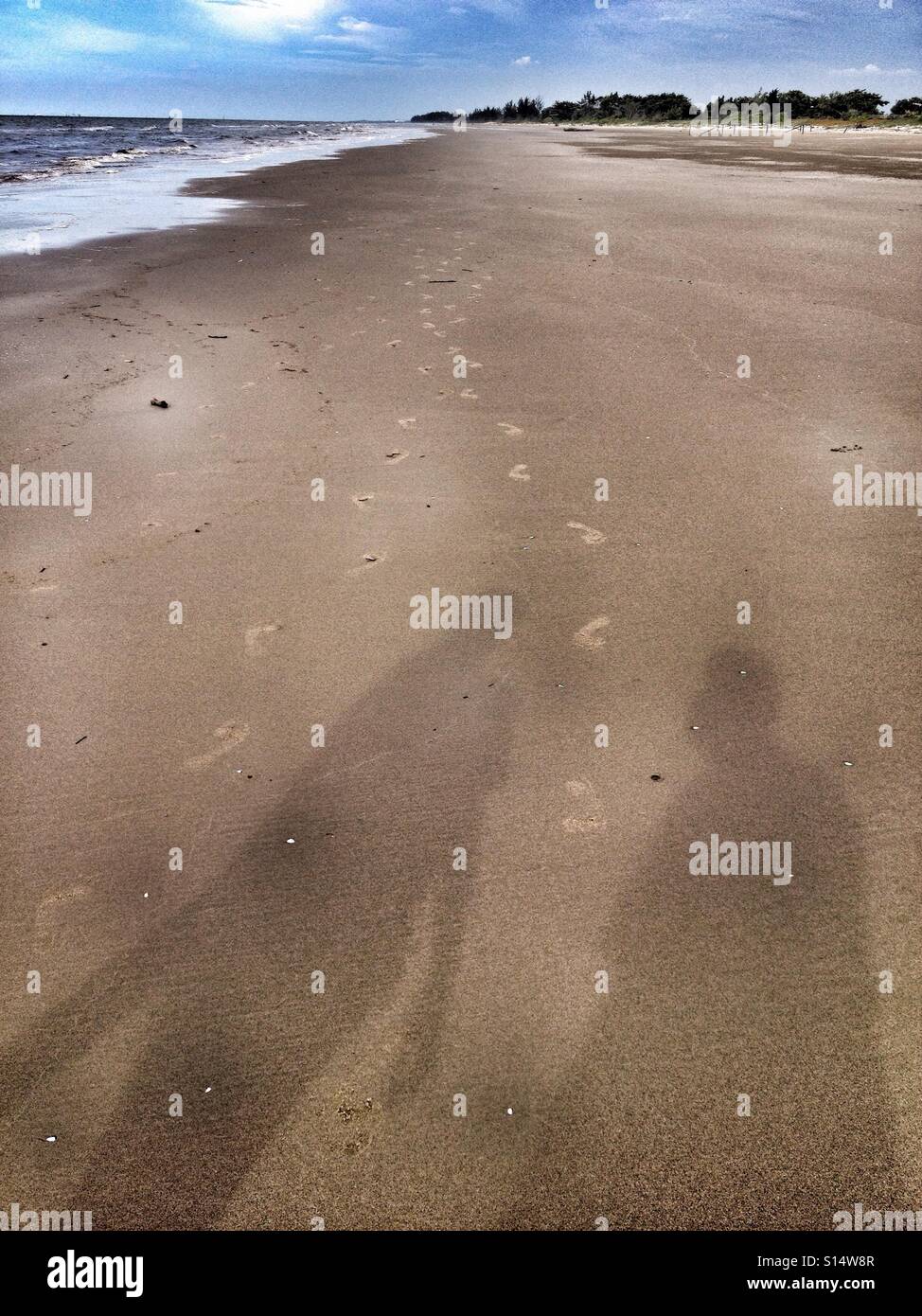 Ombre cadere sulla spiaggia sabbiosa come orme di andare e venire in tutta la sabbia Foto Stock