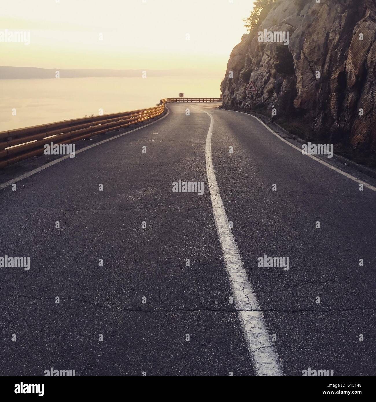 Strada di montagna sopra il mare al tramonto Foto Stock