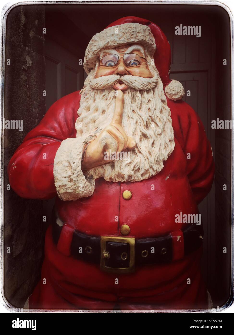 Un modello di grandi dimensioni di Babbo Natale (Santa Claus) sorge in una porta. Santa del dito è fino nei pressi della sua bocca - gesticolando a tutti di essere tranquillo e non si muove Credito foto - © COLIN HOSKINS. Foto Stock