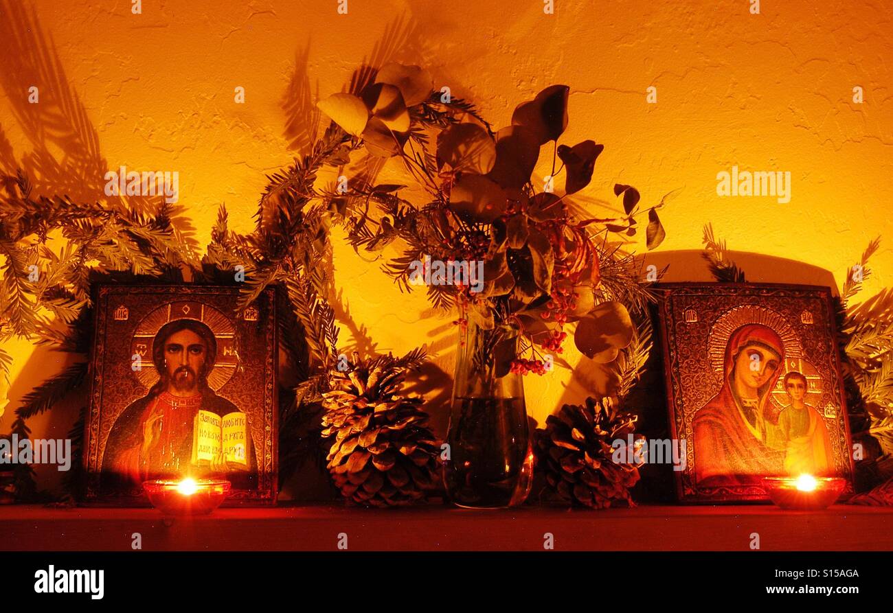 Icona russa sul mantello con rami secchi e pigne illuminato da candele per la decorazione di Natale Foto Stock