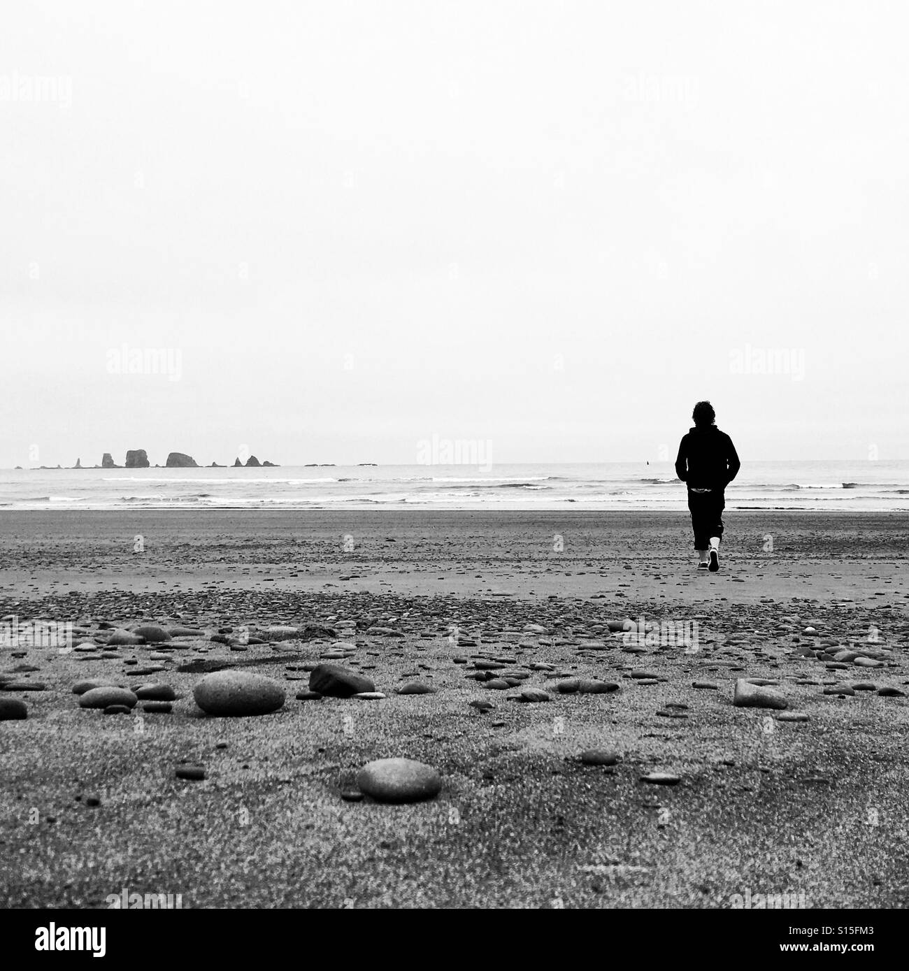 Uomo che cammina da solo su una spiaggia Foto Stock