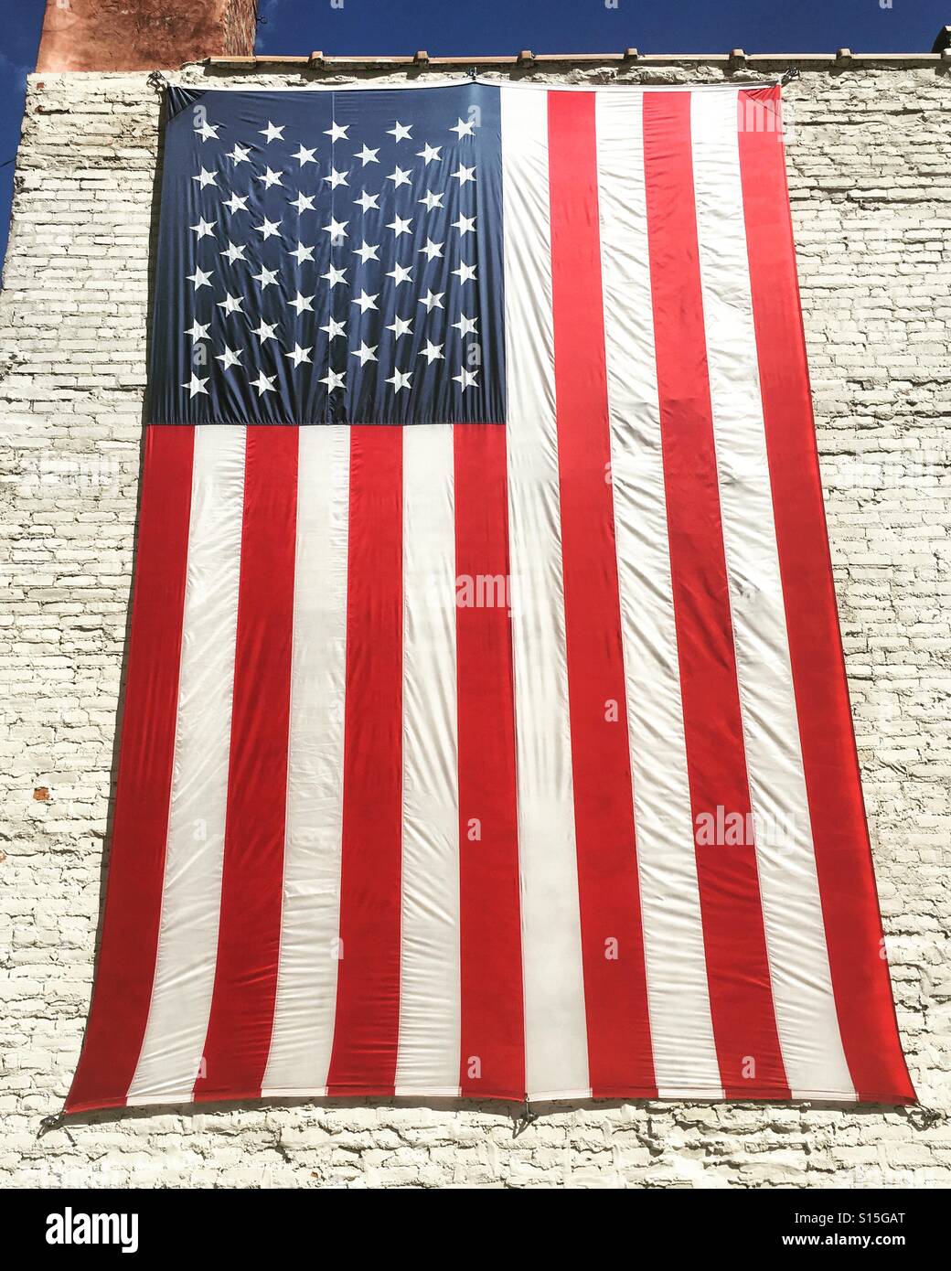 Bandiera americana visualizzata su un dipinto di bianco muro di mattoni Foto Stock