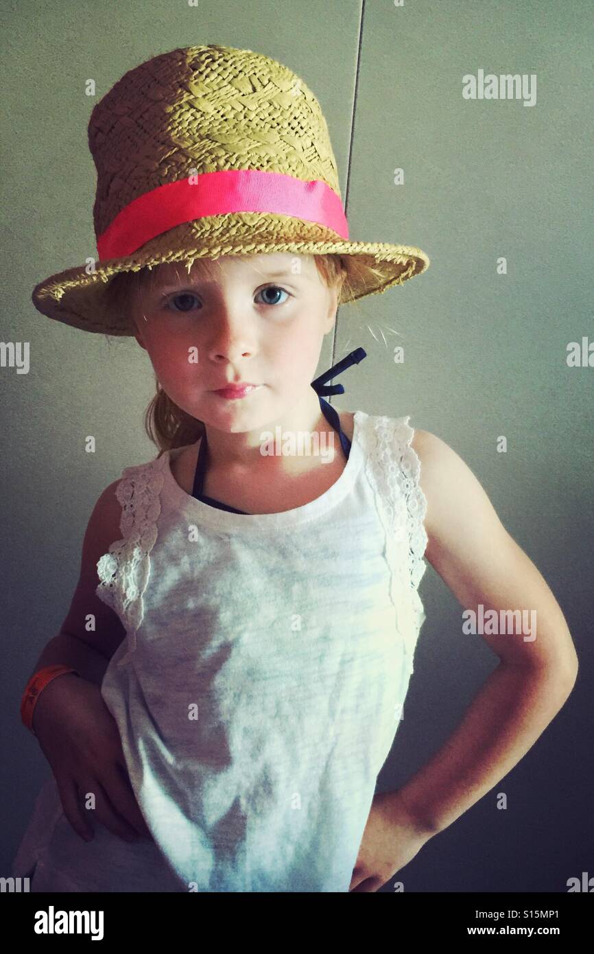 Giovani di 6 anni ragazza sassy posa indossando un cappello bianco e tee shirt Foto Stock