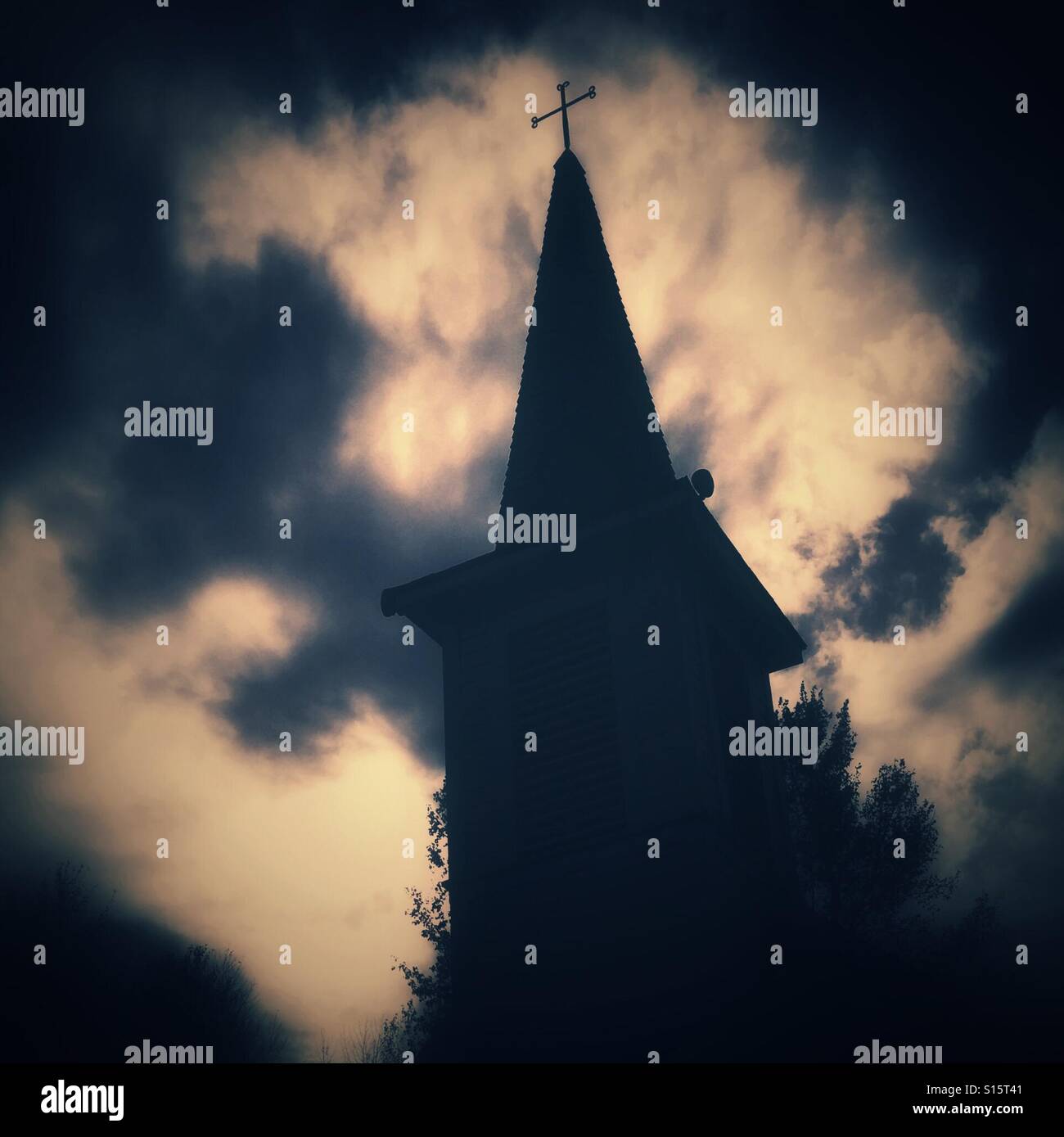 Drammatica cloudscape fotogrammi di un campanile e la croce sulla parte superiore. Foto Stock