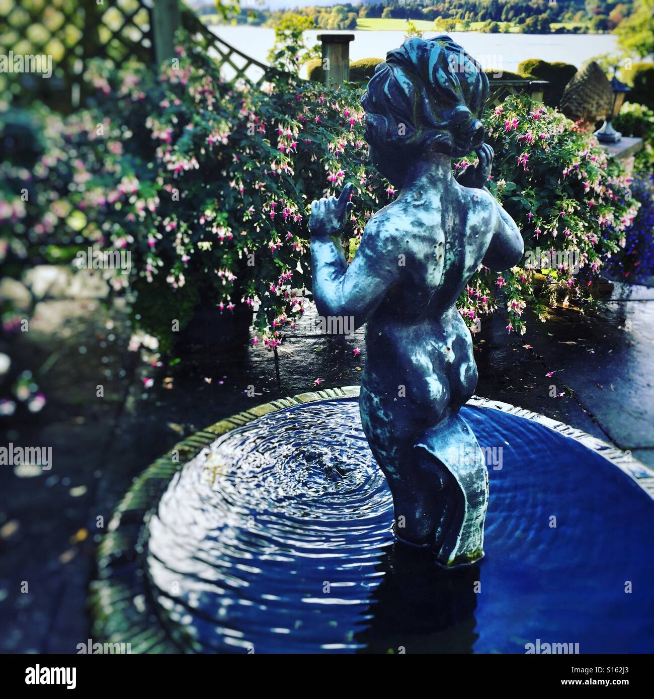 Una piccola fontana nel giardino con la statua di boy Foto Stock