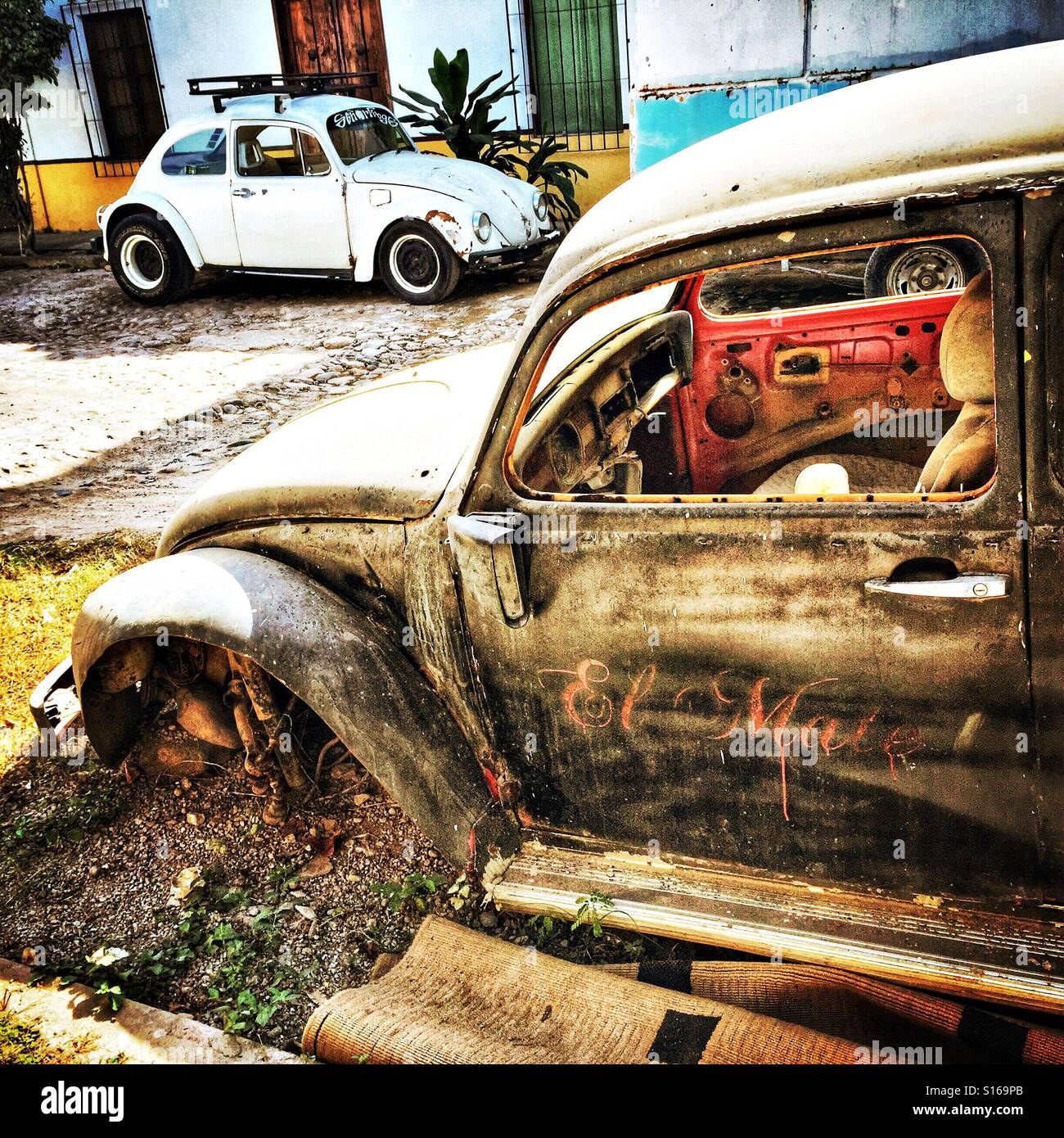 Due weathered VW bug sono parcheggiate lungo la strada da ogni altro in un paese rurale in Messico. Foto Stock