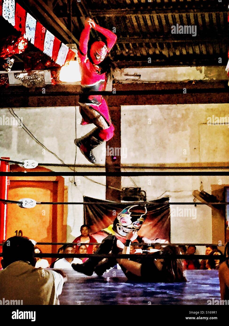 In una Lucha Lubre match wrestling tra due femmina luchadoras, una donna mascherata esegue una alta battenti manovra contro il suo avversario nell'anello. Foto Stock