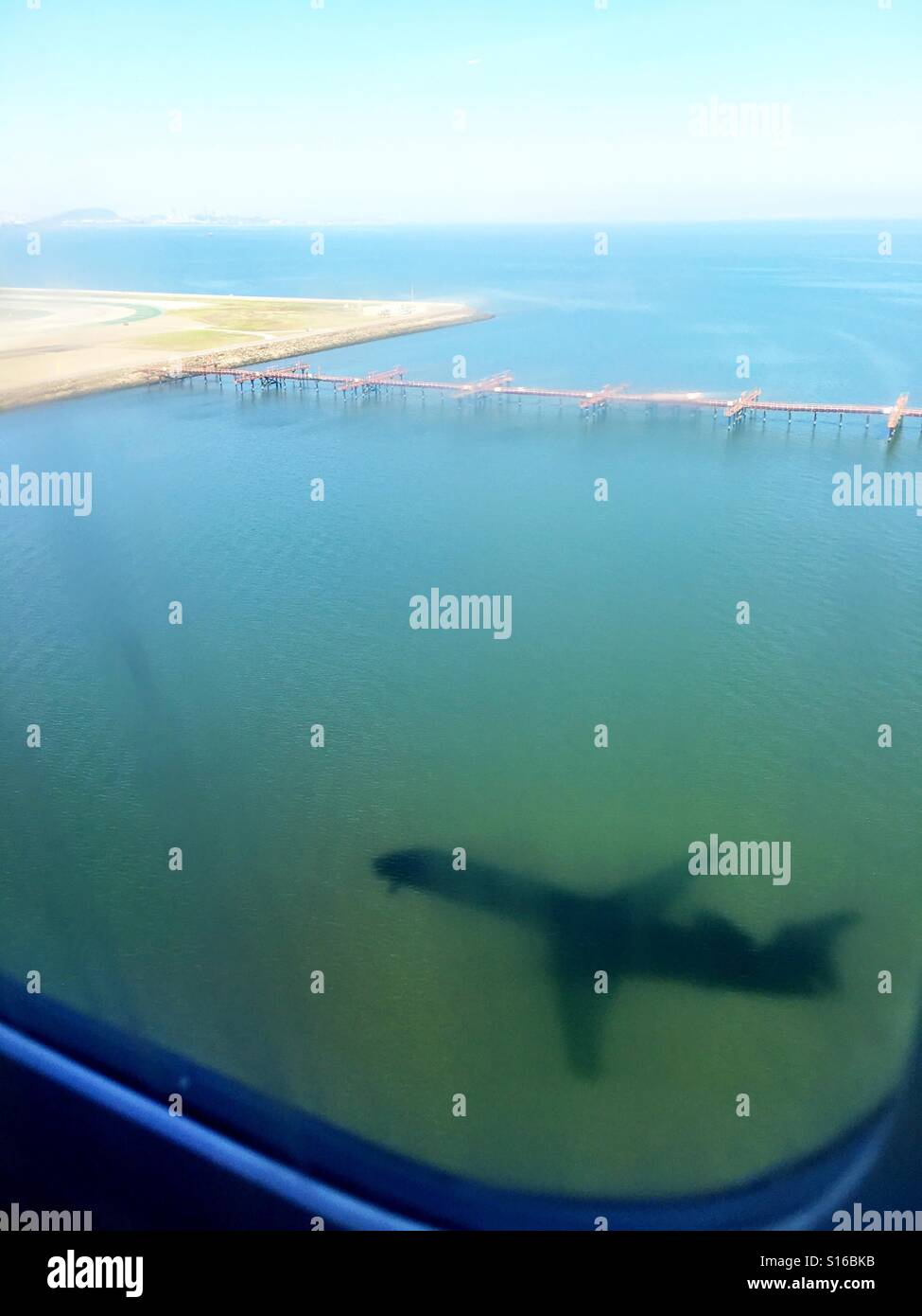 Ombra di un jet regionale come visto attraverso il finestrino per aerei come è in procinto di atterrare all'Aeroporto Internazionale di San Francisco (SFO). - Immagine stock catturata con smartphone