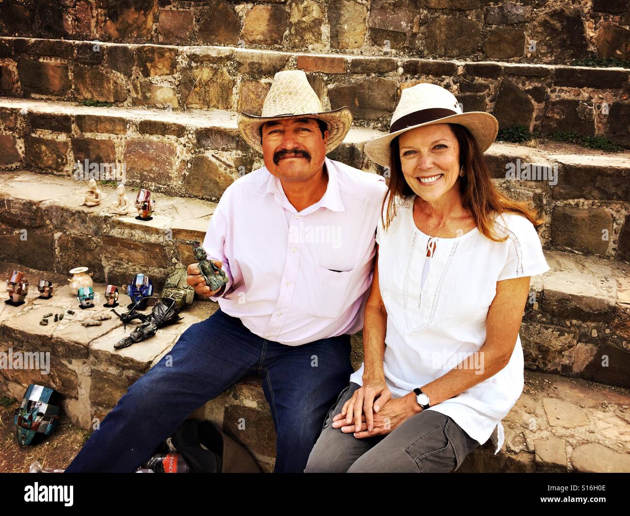 Un venditore si mette in mostra la sua bella mano figurine intagliate per un turista a Monte Alban sito archeologico, un sito Patrimonio Mondiale dell'UNESCO vicino a Oaxaca, Messico. Foto Stock