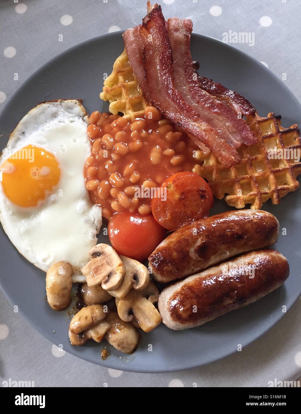 La completa prima colazione inglese. Pancetta, salsicce, fagioli al forno, pomodori, funghi, uova. Foto Stock