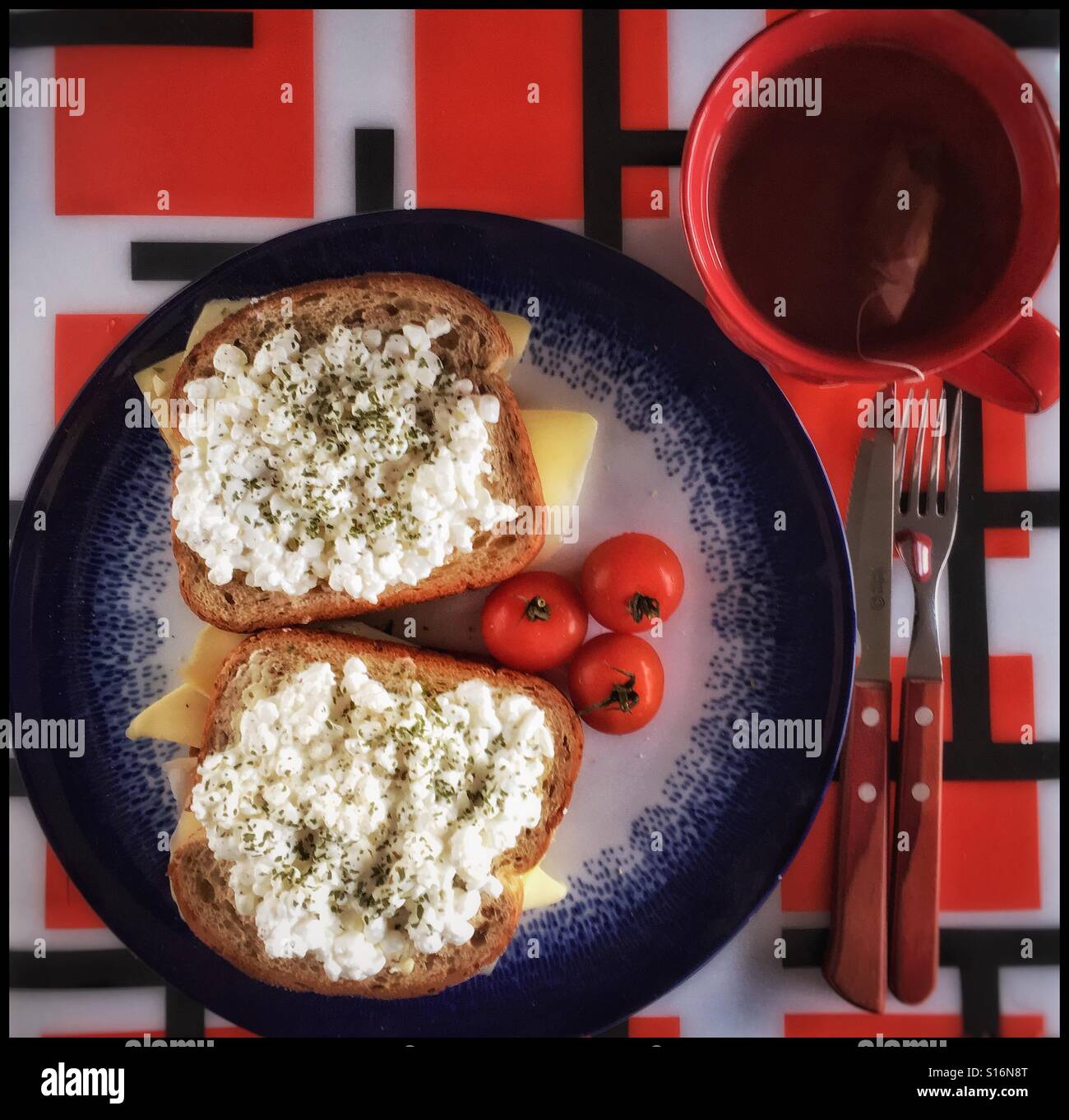 Due panini, tre pomodori e una tazza di tè. Foto Stock