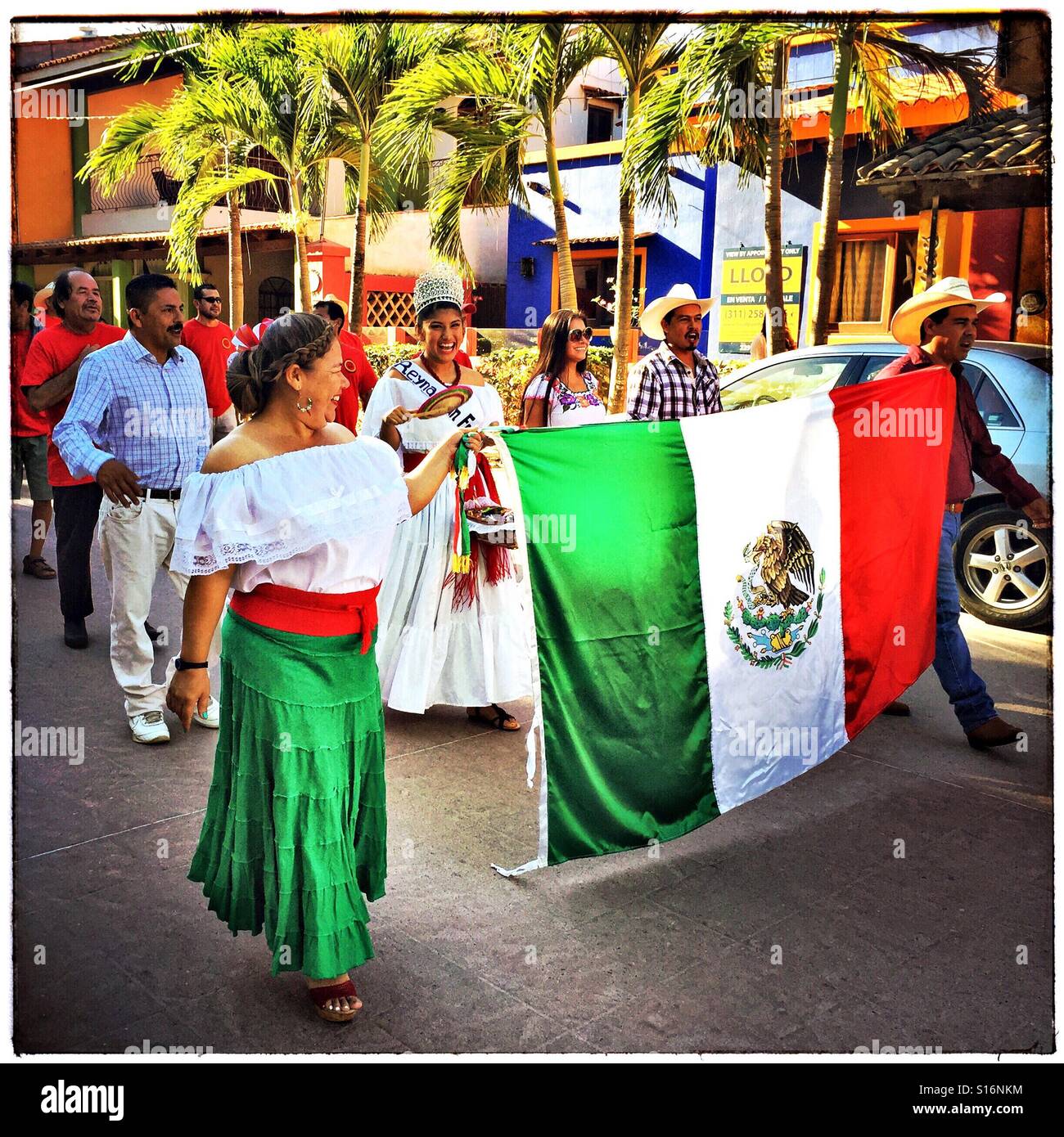 Il Día de la Revolución parade inizia con una giovane azienda la bandiera messicana. Foto Stock