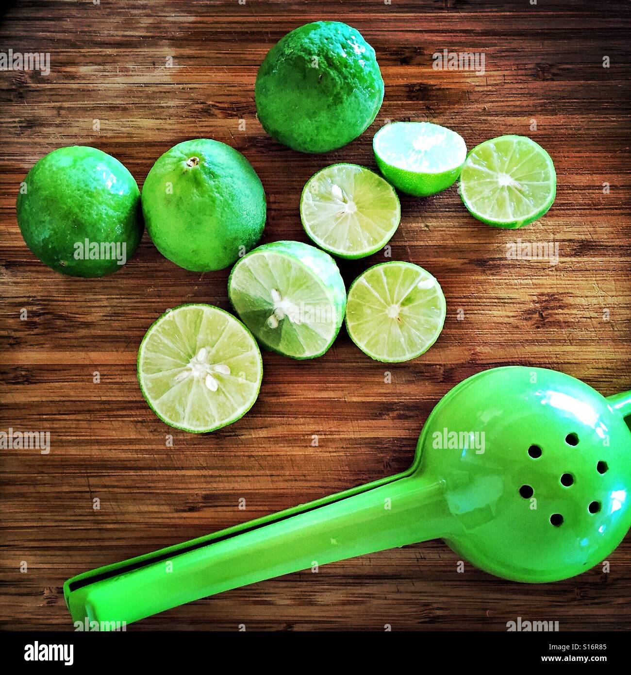 Tutto il limes e tagliare limes su un tagliere di legno con un colore lime a mano centrifuga di lime. Foto Stock