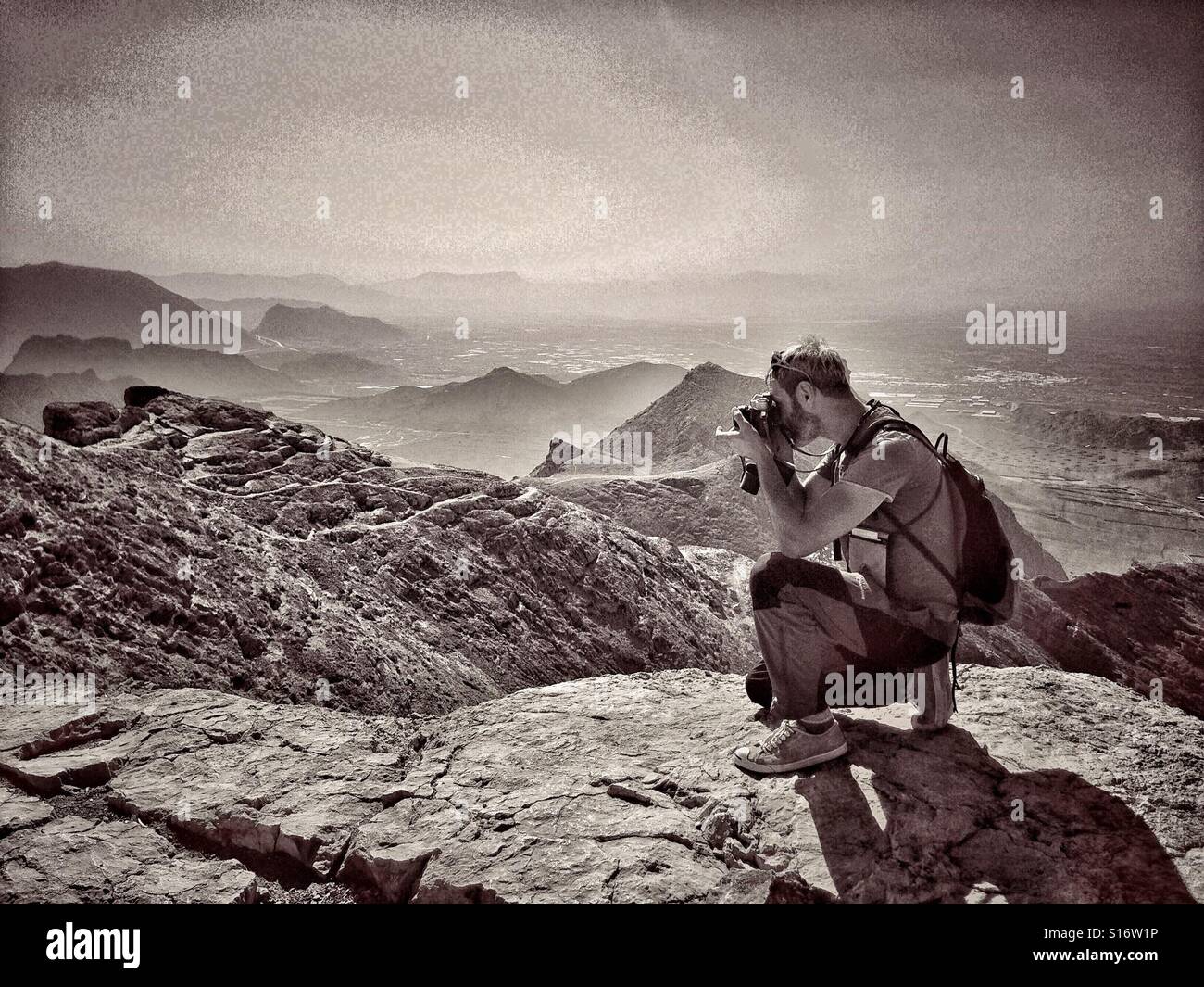 Uomo sulla cima della montagna di scattare le foto. Foto in bianco e nero - Immagine stock catturata con smartphone