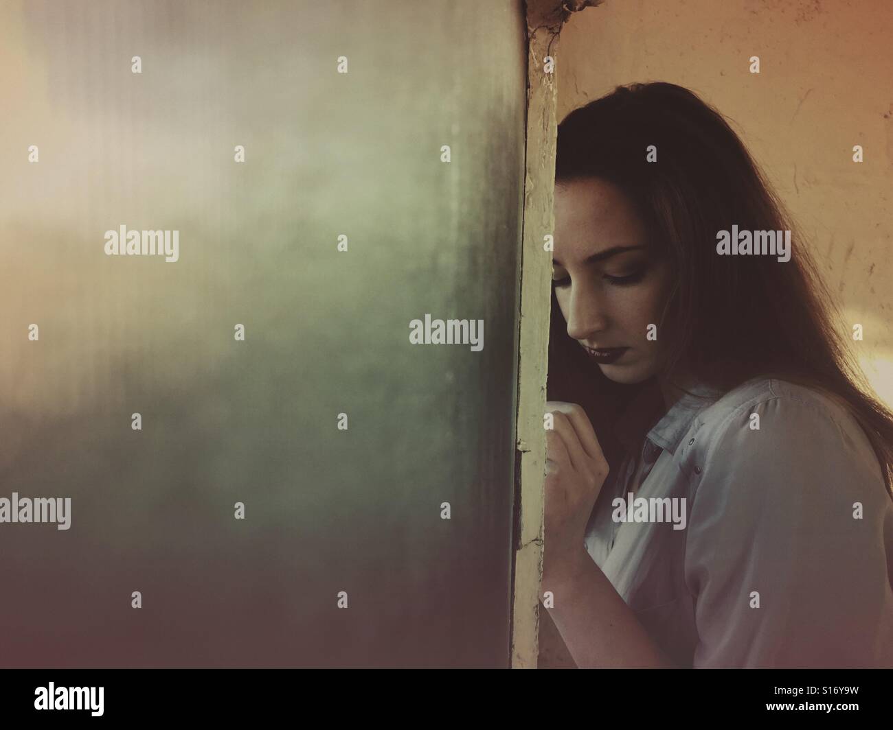 Triste donna mediante la finestra - Immagine stock catturata con smartphone