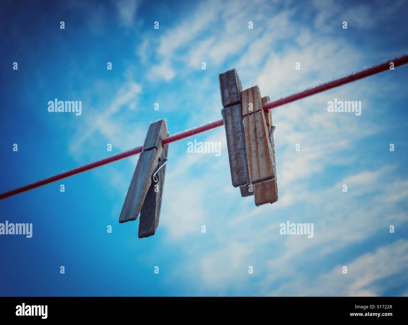 Coperto di brina abbigliamento pioli sulla linea di lavaggio contro un cielo blu Foto Stock