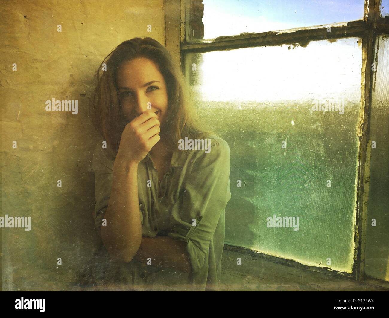 Felice donna timida mediante la finestra Foto Stock