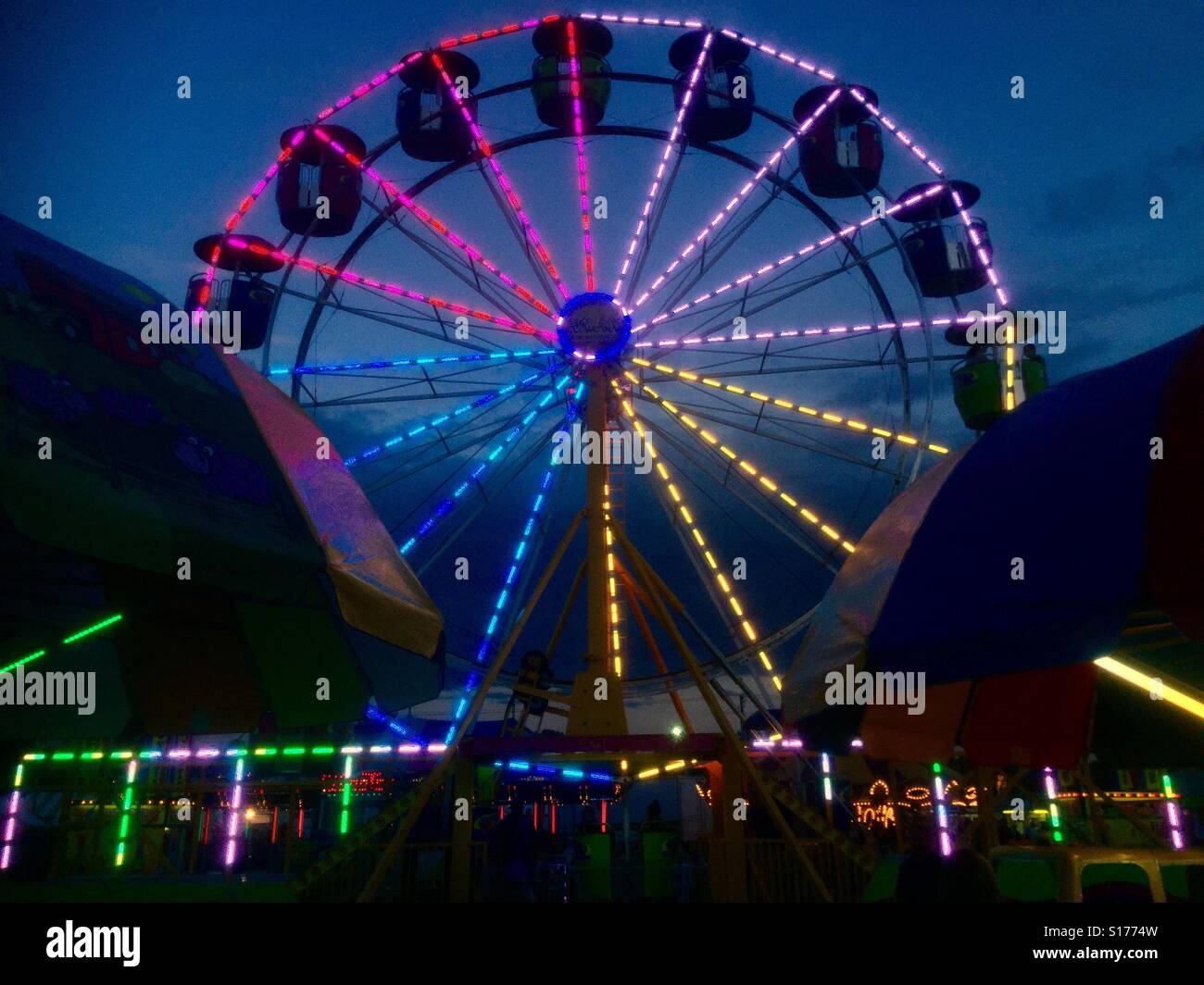 Una ruota panoramica Ferris è illuminata in molti colori di notte al carnevale - Immagine stock catturata con smartphone