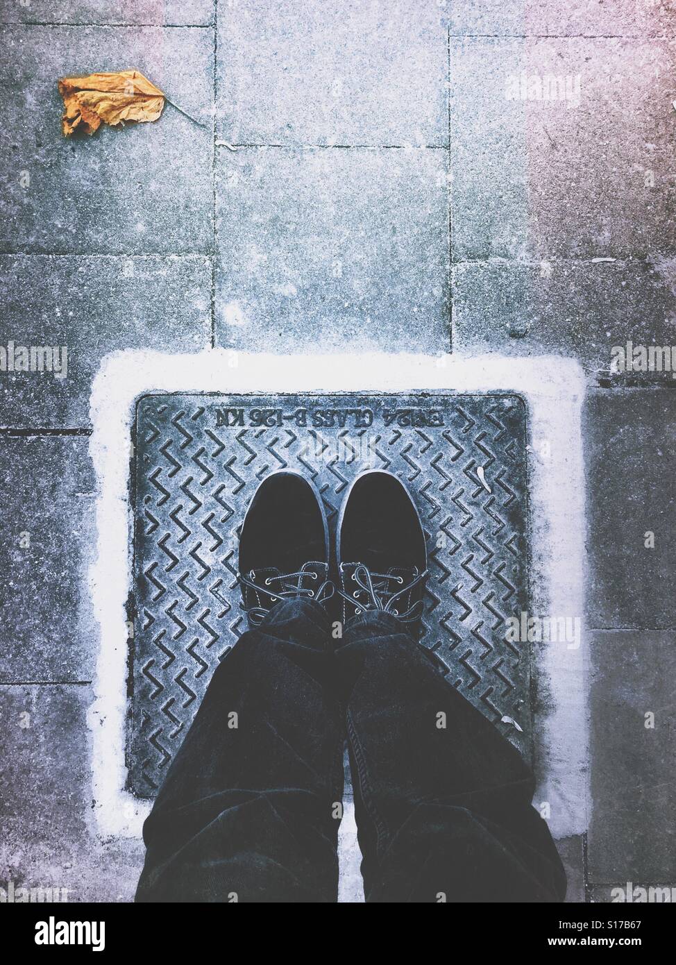 Due gambe, due scarpe, un quadrato e un autunno foglia. Foto Stock