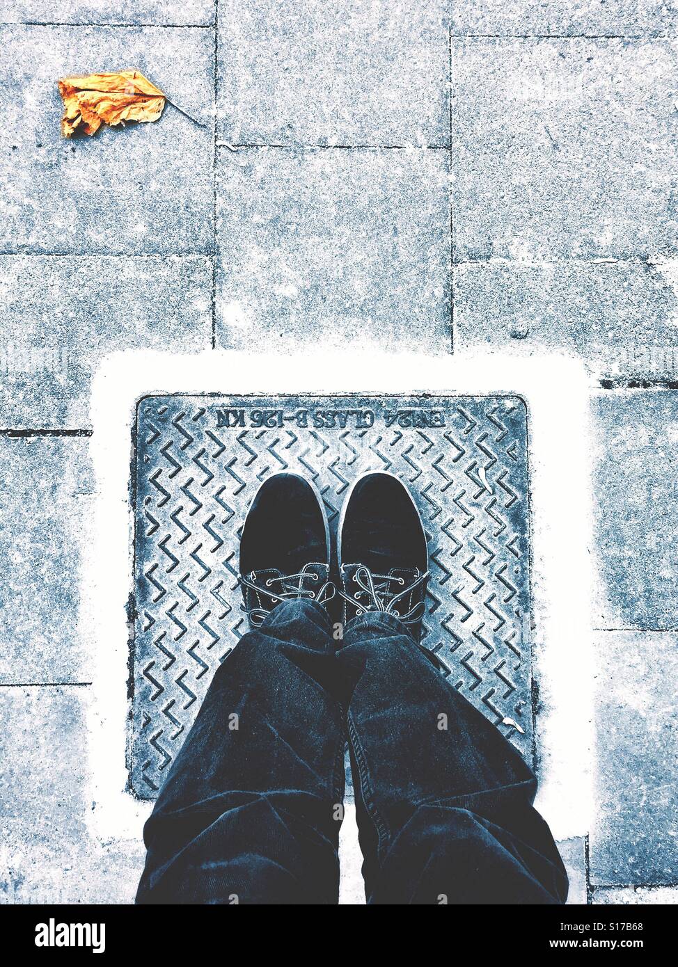 Due gambe, due scarpe, una piazza e una foglia di autunno Foto Stock