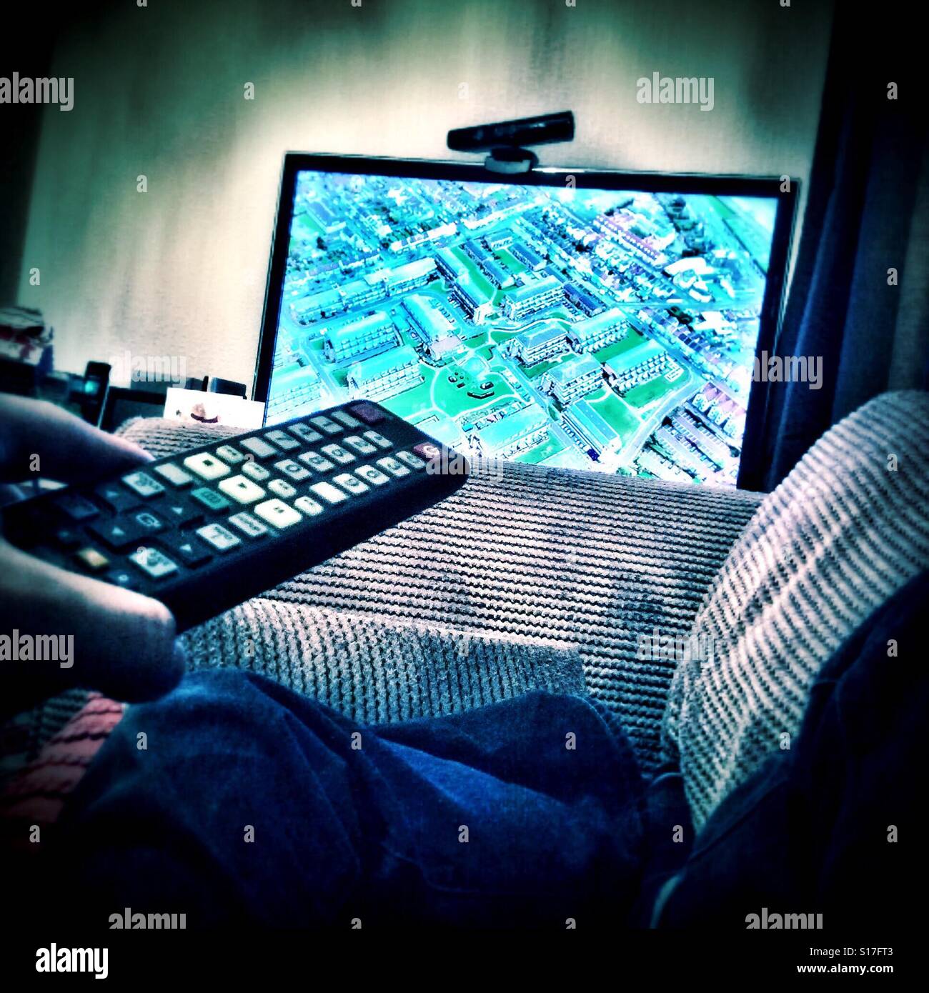 Utilizzando il telecomando del televisore per cambiare il canale. - Immagine stock catturata con smartphone