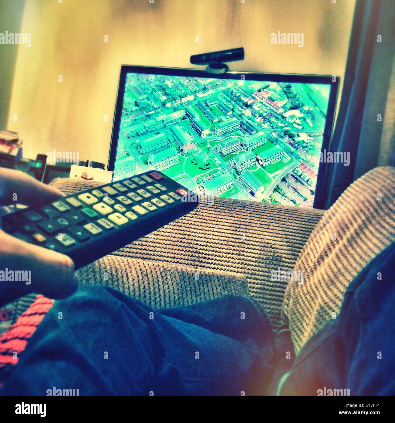 Utilizzando il telecomando del televisore per cambiare il canale. - Immagine stock catturata con smartphone