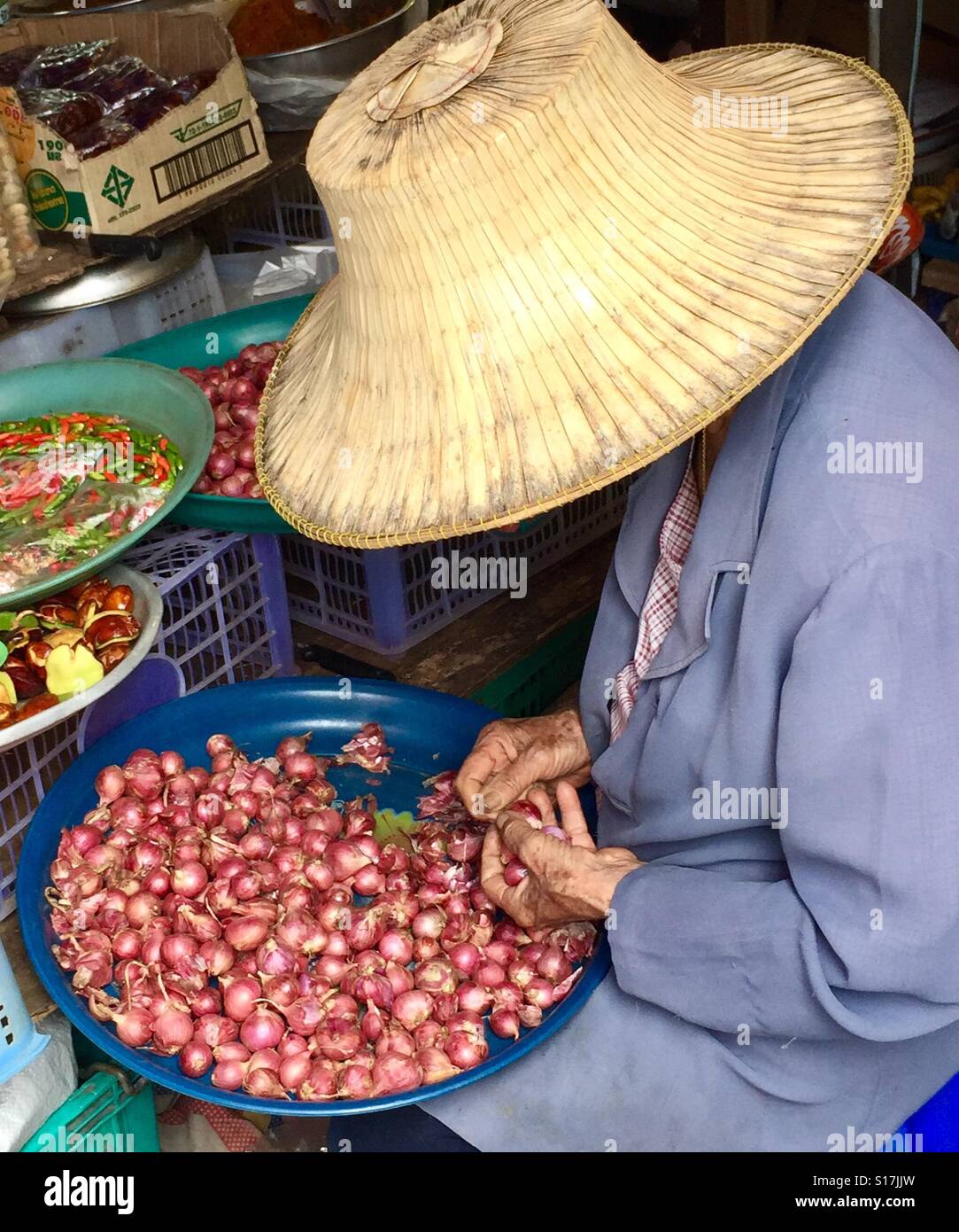 Una donna tailandese sbucciare lo scalogno nel mercato, Thailandia Foto Stock