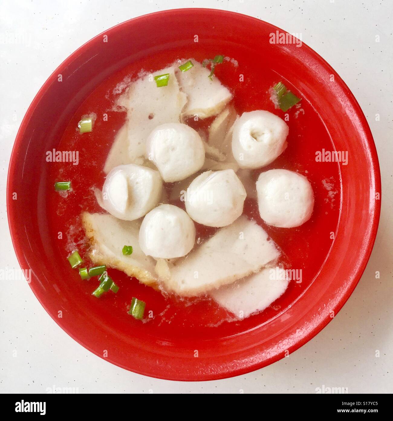Un rosso ciotola di polpette di pesce e pesce torte zuppa, Singapore Foto Stock