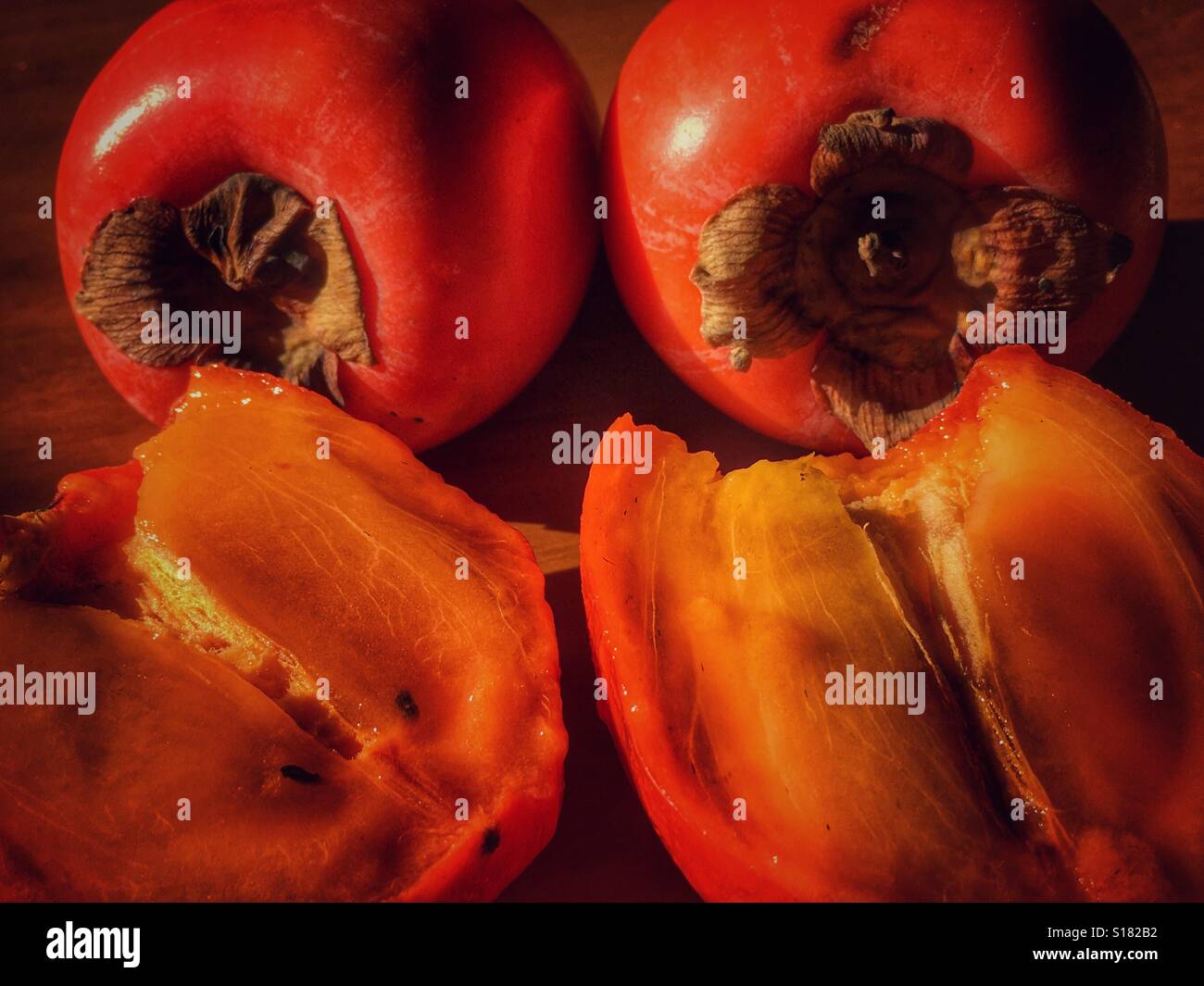 Cachi, due frutti e un taglio aperto, maturo e pronto da mangiare. - Immagine stock catturata con smartphone