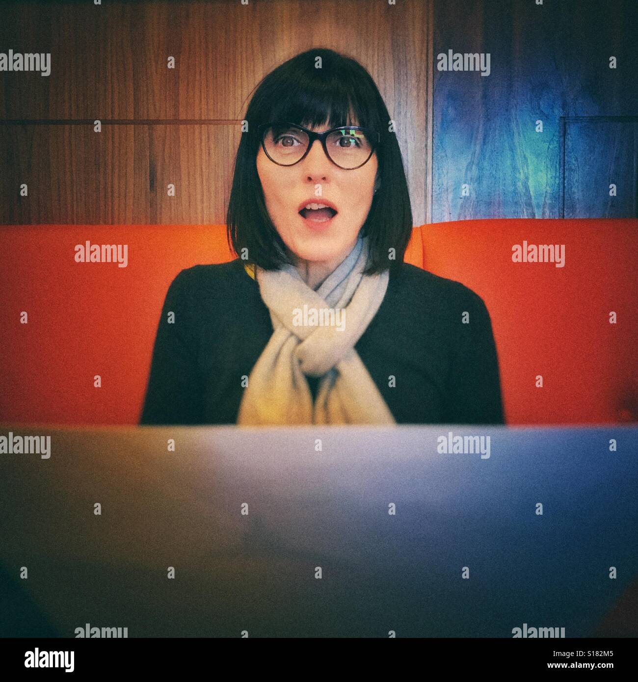 Donna tenendo premuto menu e guardando sorpreso - Immagine stock catturata con smartphone