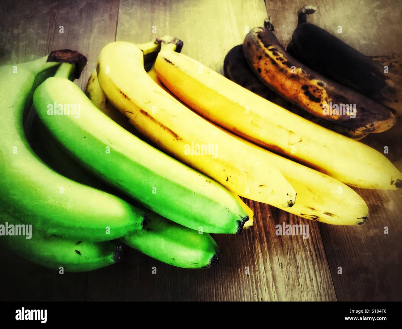 Le banane a diversi stadi di maturazione su una superficie in legno. - Immagine stock catturata con smartphone
