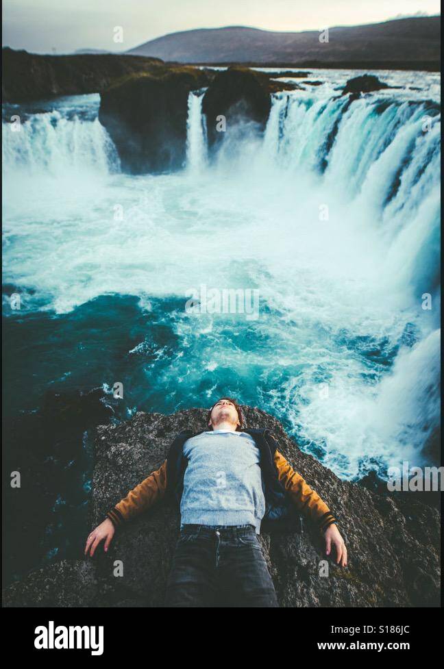 Un ragazzo guardando una cascata Foto Stock