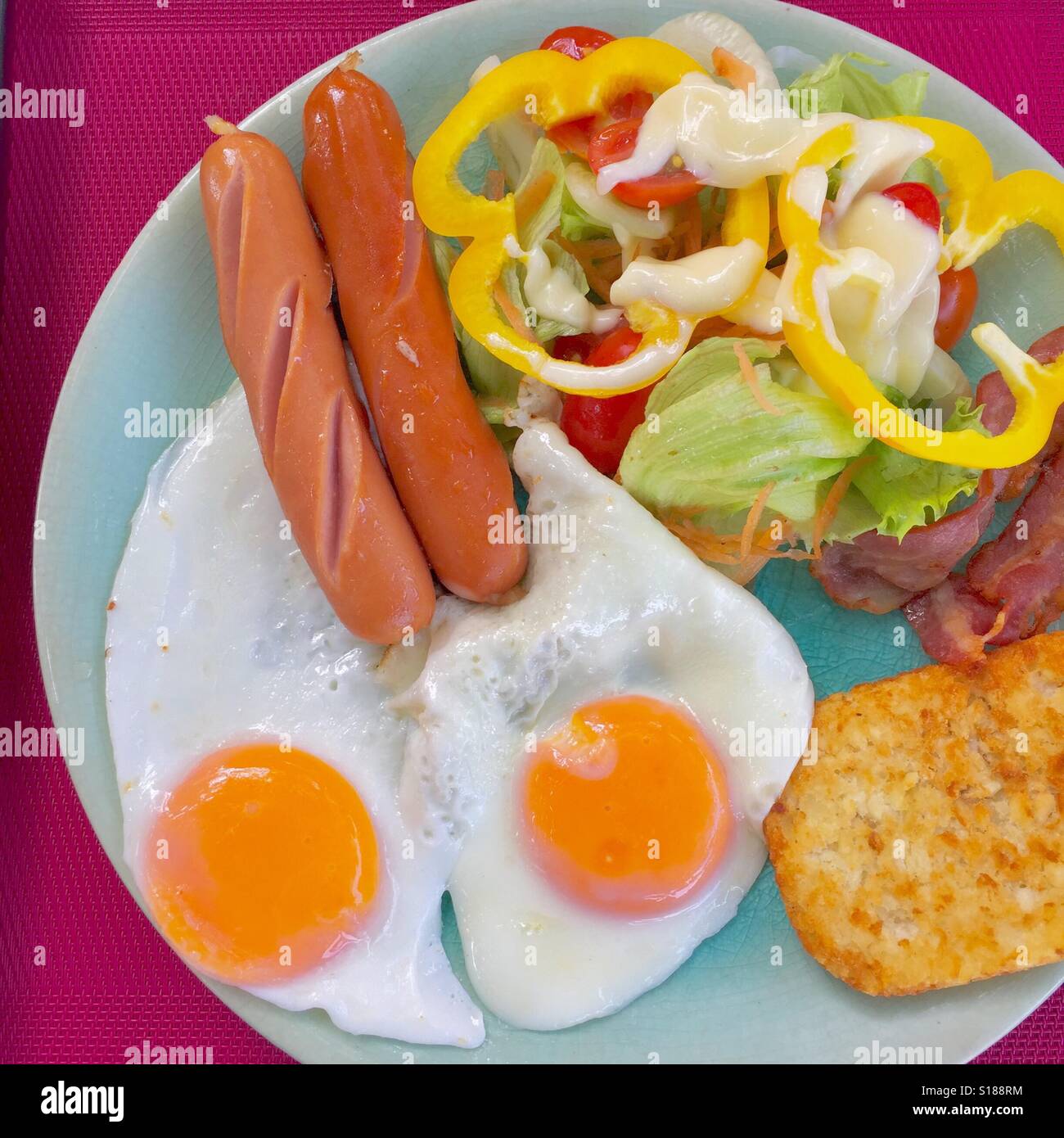 La colazione- frittura di salsicce, uova, pancetta, hash brown e insalata mista Foto Stock