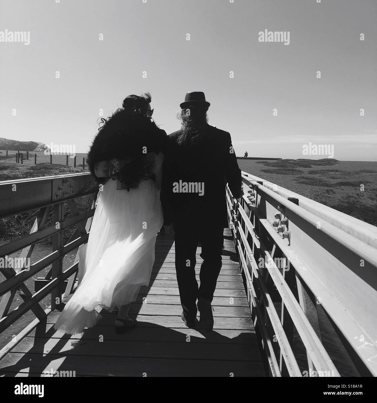 Sposa e lo sposo passeggiate verso la spiaggia Foto Stock