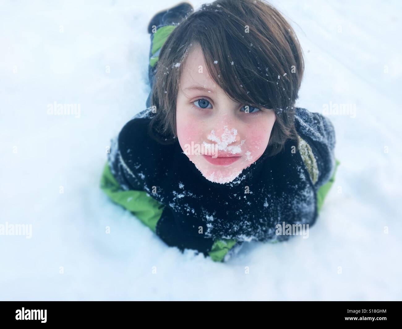 Ragazzo giovane posa in neve fresca Foto Stock
