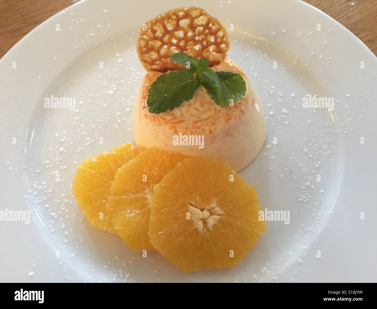 Orange panna cotta con brandy snap e fresche fettine di arancia - Immagine stock catturata con smartphone