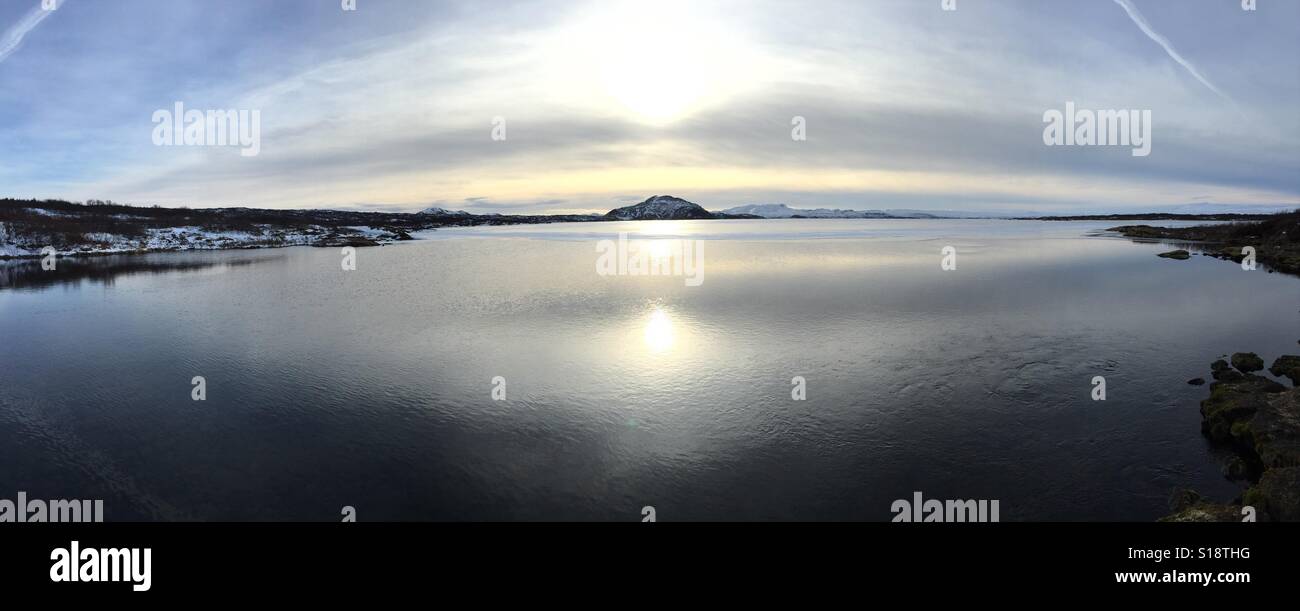 Panorama del lago ghiacciato con sun riflessione nella superficie del lago. Vicino a Thingvellir, Islanda. 2016 Foto Stock